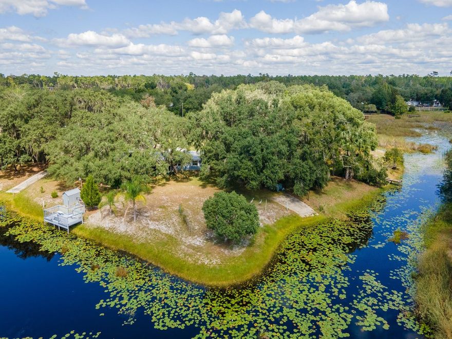 Lake Kerr Canal Waterfront Home – 23560 NE 154 Place Road, Salt Springs, FL 32134
3 Bedrooms | 1 Bathroom | Detached Loft Apartment | .52 Acres | ~235’ Waterfront | Updated Metal Roof

Discover the perfect blend of vintage craftsmanship and waterfront tranquility in this charming canal-front home located in the desirable Sherwood Forest subdivision on Lake Kerr in beautiful Salt Springs. Situated on .52 fenced acres with approximately 235 feet of canal frontage, this property offers endless outdoor enjoyment, privacy, and space to entertain.

The main home, built in 1963, features 3 bedrooms, 1 bathroom, and 1,276 sq ft of living space. Constructed with solid, old-fashioned craftsmanship, this home exudes character and charm. Inside, you’ll find a cozy kitchen with a center island and stainless-steel appliances, a Florida stone wood-burning fireplace with mantel, and an open living and dining layout. The bathroom features a tiled tub/shower combo, and all bedrooms are comfortably sized. The 9’x15’ screened porch overlooks the beautifully landscaped yard and canal, perfect for enjoying your morning coffee or evening sunsets.

The detached loft apartment, located above a two-bay carport, offers a private retreat with an open living space and full bathroom—ideal for guests or potential rental income. The lower level includes a laundry room, storage area, and additional space perfect for tools, a lawn tractor, or workshop needs.

Outdoor living shines here, featuring multiple covered parking areas, an attached storage shed, and a metal two-car carport with concrete pad. The yard is lushly landscaped with mature oaks, palms, grape vines, and tropical plants, all adding to the serene setting.

The dock at the water’s edge includes a fish cleaning station with water and power, offering easy access for boating, fishing, or simply relaxing by the water. Enjoy the peaceful zen-like garden area with moss-draped trees and breezy canal views.

Lake Kerr, a 2,800-acre spring-fed lake and Marion County’s second-largest, connects to Little Lake Kerr (Lake Werner) and offers world-class fishing for bass, bream, catfish, and specks, as well as exceptional opportunities for boating, wakeboarding, kayaking, and tubing.

Located in the heart of the Ocala National Forest, you’re just minutes from the Salt Springs Recreation Area, Lake George, and the St. Johns River. The area also features miles of ATV, horseback, and hiking trails, plus year-round fishing, hunting, and natural springs. Conveniently close to local shopping, restaurants, and just 30 minutes to Ocala or Palatka.

This is a rare opportunity to own a property that combines vintage charm, modern updates, and exceptional waterfront access—ready for you to enjoy the Salt Springs lifestyle!
