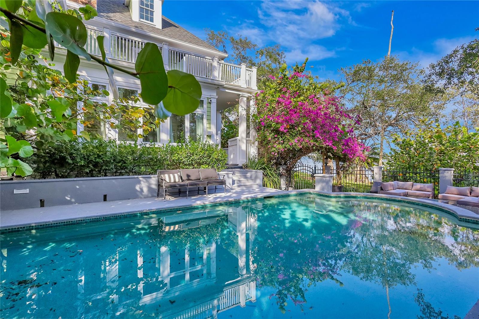 This extraordinary South Tampa estate is the latter: a private, 340-foot bayfront sanctuary set on nearly an acre of pristine land, bordered by a protected Florida preserve and lovingly transformed into a thriving bird sanctuary and natural refuge. A place where endangered native species flourish, bay breezes carry songbird calls, and the land itself rises in quiet protection.
Here, nature isn’t a backdrop, it’s your guardian. Towering oaks, deep rooted native trees, and flourishing mangroves form a living ecosystem that filters and purifies the water it touches. These natural defenses paired with expert engineering have kept this estate remarkably dry. This home has never flooded. The grounds unfold into a private beach like shoreline lined with native mangroves, offering a peaceful, protected connection to the bay. A newly installed custom fence adds discreet security and opens to a separate access point on the far side of the home, perfect for service, events, or private guest entry.
Elegance and soul live side by side in this Plantation style masterpiece. Inside, five fireplaces flicker across spaces designed for grand entertaining and intimate moments alike including in the master suite and even within a hidden dressing room. The chef’s kitchen is both indulgent and functional, featuring Carrera marble, a gas range, and panoramic bay views.
Walls of windows open to a radiant sunroom, framing sweeping views of the saltwater heated pool, private beach, and endless open water. French doors lead to deep wraparound porches on both levels, where the sky paints a new masterpiece each sunrise and sunset. Every bedroom offers a private en-suite bath, and a full additional bath on the main floor provides seamless access from outdoors.
Ascend to the third floor and discover a full private suite complete with its own kitchen, bath, and generous living space, ideal for extended guests, multigenerational living, or inspired creative retreat.
This is not just a luxury home. It is a rare, living ecosystem, crafted by hand and heart where nature protects, elegance prevails, and every sunrise feels like a personal gift from the bay.
This home has a beautiful story and elegant nature protected presence like no others.