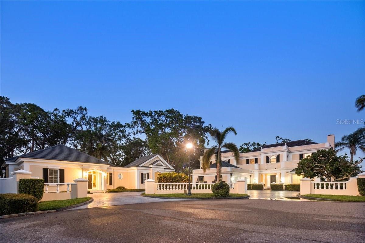 Tucked away in a quiet cul-de-sac on a double lot beneath majestic oaks, this almost 5,000 sq ft, timeless 2-story home blends sophistication with modern comfort. Situated on the first hole of Heron Golf Course, the home features soaring 11-ft ceilings, marble floors, and crystal chandeliers. A Louis XVI fireplace anchors the sunken living room, while French doors and expansive windows invite sunlight into the sunroom with breathtaking golf course views leading to three patios perfect for entertaining or relaxation. A brick path winds through lush gardens to the adjacent guest house. This nearly 2,000 sq ft guest house features 2 bedrooms, 2 en-suite bathrooms, a spacious living room, dining room, an outdoor kitchen, and a private laundry room. Overlooking the pool and spa, this guest retreat offers privacy and convenience, ideal for extended stays, visiting family, or in-law suite. The Oaks club amenities include 2 18-hole championship courses, and world-class tennis and pickleball facility. Located near Casey Key and the powdery white sands of Siesta Key. Enjoy the arts in Downtown Sarasota and shopping at St. Armands Circle; approximately a 20 minute drive. Membership at The Oaks is required.