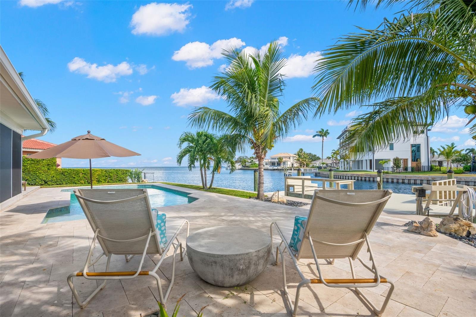 Welcome to your private paradise located on Mermaid Point NE, a secluded street within the highly desirable waterfront neighborhood of Venetian Isles. The home was completely renovated in 2017/2018 with attention to every detail. It features a split-bedroom floor plan with 2,229 sq. ft. of living space, including 3 bedrooms, 2 ½ bathrooms, and an all-purpose utility room.
The heart of the home is the Chef’s kitchen, featuring Viking appliances including a double French door wall oven, warming drawer, French door refrigerator, gas cooktop and hood, dishwasher, and microwave. The oversized full-slab island hosts the cooktop, microwave, seating, and plenty of countertop space. The kitchen also offers abundant storage, including three double pantries with custom rollout trays. A triple impact sliding glass window highlights the water views from every angle. The living space includes a formal sitting area, dining room, and a family room with a gas fireplace and a triple impact sliding glass door to capture sweeping bay views. The Owner’s suite features a large picture window overlooking the water, crown molding, custom window treatments, and an expanded spa-like bathroom with a large walk-in shower, slipper tub, private water closet, and double sinks. The enlarged walk-in closet includes custom cabinetry and a back door for easy access to the laundry room. The east side of the home offers two guest bedrooms, a guest bathroom, and a hall closet.
The backyard has also undergone a complete transformation, creating a tropical oasis highlighted by open water views. It features a custom heated saltwater swimming pool with LED lighting, a swim shelf with bubblers and umbrella holder. A large travertine deck surrounds the pool. An additional outdoor entertaining area includes a large dock (20x12) with a walkway (4x30) leading to your boat lift. The dock features built-in benches, railings, a fish-cleaning table, lighting, power, and water. A large screened in patio (32x18) completes the entertaining area of the backyard. Additional improvements include: a raised seawall with oversized cap, aluminum black fencing, landscape lighting, and mature tropical landscaping.
House systems have also been upgraded and added, including: a Generac whole-house generator, Carrier A/C system, impact windows, French doors, sliding glass door, and front door, Halo water system, Honeywell alarm system, upgraded electric panel, Rheem gas water heater, new hot and cold water plumbing lines, Turner Pest Control monitoring system, seamless gutters, sprinkler system, exterior lighting, and a stamped concrete driveway and walkway.
You can also grab your kayak or paddleboard for a short trip to Weedon Island. The location allows for easy access to Downtown St. Petersburg, the beaches, and Tampa International Airport, which is just a short drive away.