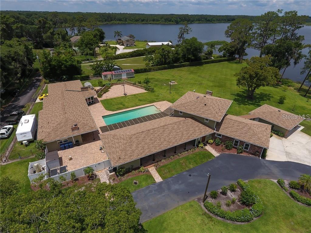 Discover a one of a kind, lake front multi-generational estate! This exceptional property offers a rare blend of privacy, comfort, and versatility—it truly has it all! Set lake front on Lake Talmadge in DeLand on a sprawling 2.65 acres, featuring a spacious main home, two fully equipped in-law residences, 2 garages, a pool, amazing views, and more! The main home features 3 bedrooms with 3 full en-suite bathrooms and powder room, a gourmet kitchen, butlers pantry, 2 fireplaces and more. The unique qualities are evident from the moment you step through the grand carved oak doors. Chicago brick paves your way through the foyer to the massive great room, featuring luxury vinyl flooring, custom crown molding, and walls of windows. Designed for both the aspiring home chef and effortless entertaining, at the very heart of the home, the gourmet kitchen is as functional as it is breathtaking. Featuring high-end stainless steel appliances, custom cabinetry, Brazilian granite, gas range with pot filler. The open layout flows seamlessly into the surrounding living and dining areas, while the wood burning fireplace and lakefront views create a backdrop of natural beauty while you cook, dine, or entertain. Adding to the homes functionality, is a thoughtfully designed butlers pantry complete with custom cabinetry, stainless steel sink, granite counters, and a huge walk-in pantry. Retreat to the expansive upstairs primary bedroom, a serene retreat designed for both luxury and relaxation. Enjoy breathtaking views while a wood burning fireplace adds warmth and charm. The suite also features 2 custom closets and a luxurious en-suite bathroom complete with soaking tub, shower, and double vanity. The primary home also includes 2 downstairs bedrooms with 2 full en-suite bathrooms, and indoor laundry room, and a 24x26 garage. Primary home updates and features include Roof 2018, HVAC 2015, Tank less W/H 2015, updated Electric 2015, FAS Windows 2024. Adding to its exceptional versatility, the estate also includes two fully equipped in-law homes. Thoughtfully designed, each in-law home includes 1 bedroom, 1 full bathroom, fully updated kitchens, private entrances and beautiful pool and lake front views. The in-law homes provide privacy, comfort and modern conveniences to family and guests. Updates and features to the in-law residences include, Roof 2018, New Mini Splits, Tank-less W/H 2015, Updated electric 2015, FAS Windows 2024, custom closets and cabinetry, 1- wood burning fireplace, 1 -24x25 garage with W/D hook up and new ceiling. Step outside and experience the true beauty of this lakefront estate’s outdoor living space. The expansive grounds feature paved raised garden beds, as well as a dedicated greenhouse for year-round cultivation. Surrounding the property, you’ll find a variety of mature fruit trees that provide abundance and charm. At the center of it all is a sparkling 50x20 pool with unobstructed views of the lake, creating a resort-like atmosphere and true outdoor Florida lifestyle. Exterior property updates include: Gas Powered home Generator, Property Reverse Osmosis Water Filtration System, New Pool pump 2023, New Well Pump 2023, 3 septic tanks, 500 gallon LP tank underground, Resealed driveway 2025, Exterior Paint 2025, Fully Fenced, 12x30 shed and 8x12. This property is a rare offering that has it all! Take the opportunity to own your multi-generational paradise and schedule your showing today.