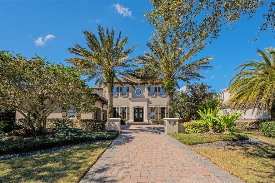 Prime location for what was once Lee Wetherington's Model Home in Phase 1 of The Lake Club. This luxurious custom home is a rare opportunity for a residence on Waterton Lane which was originally this community's model row with elevated standards. From the moment you approach this property you will take note of the elegant architectural details and fine craftsmanship. Top quality throughout this open floor plan with designer selected finishes, travertine floors, gas fireplace; and spacious outdoor living area. The Chef's kitchen includes gas range, granite countertops plus a large island (apx 9'x8') with brand new quartz surface. Disappearing sliders from the main gathering room lead to a grand covered lanai with outdoor kitchen and motorized drop-down screens. The outdoor living space with a waterfall, pergola and Romeo and Juliet Balcony exudes a romantic ambiance. The saltwater swimming pool includes a sun shelf, spa and integrated fire pit. Plus, there's an iron gate leading to the lakeside seating area with mature landscaping for a peaceful retreat. There's space for everyone in this beautifully designed home with 4 Bedrooms, 4 Ensuite Baths, Pool Bath, 2 Powder Baths, Den, Grand Room, Gathering Room, Dining Room, Covered Lanai, Veranda, Bonus Room and 3 Car Garage. With two lake views, this home offers scenic views for both sunrise and sunset. Conveniently located across the lake from the community's amenity center. The Lake Club lifestyle has so much to offer with its luxurious amenities featuring a Grande Clubhouse with dining and special events; tennis and pickleball; fitness center; swimming pools and concierge services.