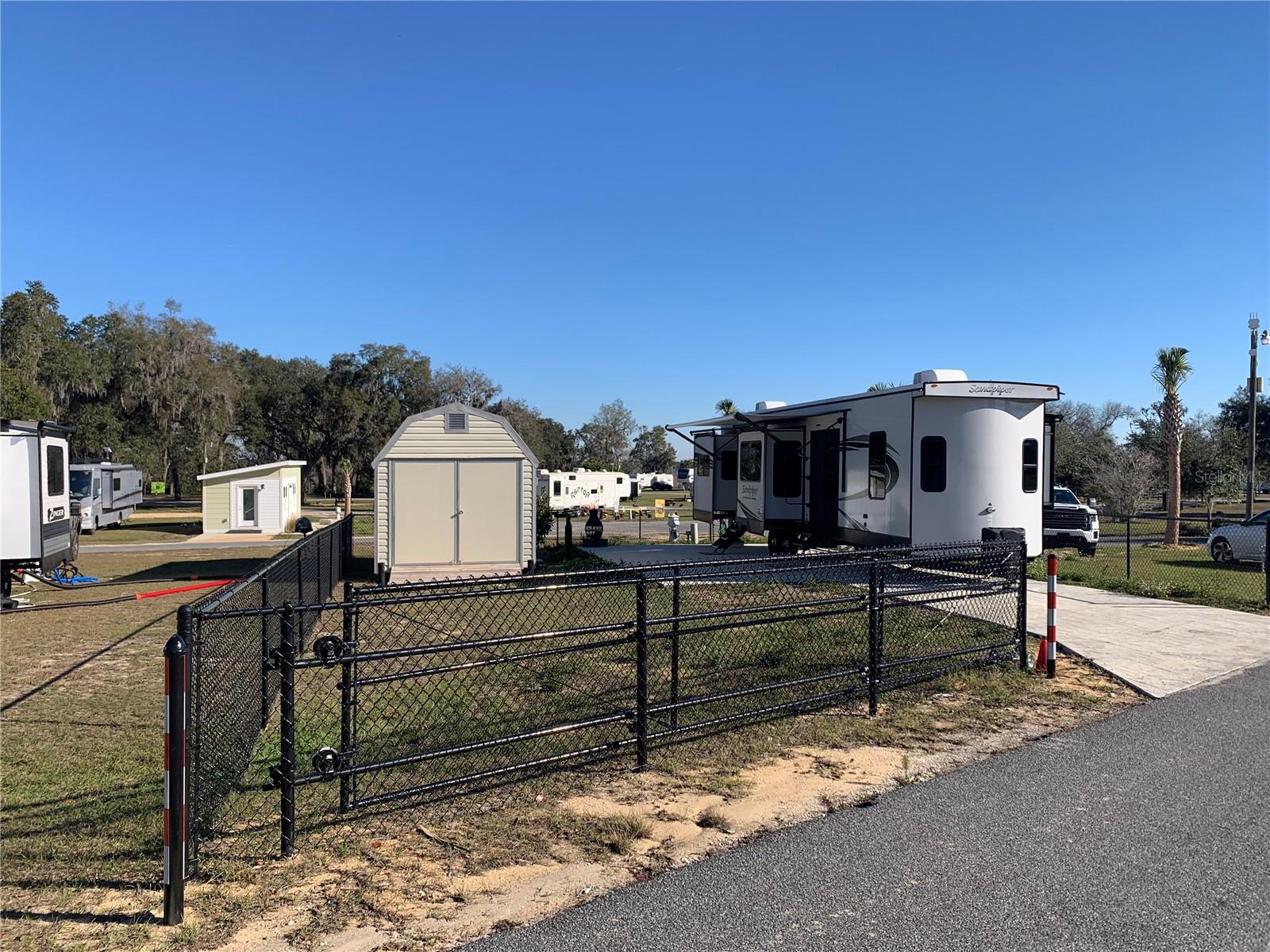 Lake Oklawaha Resort ~ Deeded CORNER FENCED lot with GATE with green space next to it. Concrete driveway. Large SHED. Includes fire chimney and 4 person pop-up tent. Great opportunity to live here, use as a weekend retreat or as an investment property ~ AirBnB/Vrbo! Amenities for all ages include a pool, clubhouse, laundromat, dog park, beach area, playground, corn hole, volleyball, ATV riding trails, nature trails to lake and outlook, and much more. Close to downtown Fort McCoy with grocery store, doctor's office, pharmacy, hardware, gas station, pizza delivery and 30 miles to Ocala's conveniences. For the outdoor enthusiast, lakes, springs, and Ocala National Forest are close by for you to enjoy fishing, hunting, hiking, canoeing/kayaking, and ATV trails! HOA includes electric, water, sewer, trash, and amenities. RV is available for sale separately for $58k.