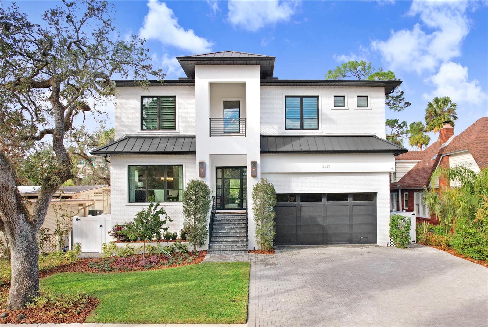 Nestled in prestigious Sunset Park neighborhood, this exquisite 2-story luxury residence built by Baywalk Custom Homes on oversized 157 foot deep lot offers unparalleled luxury with 5BRs, 5.5BAs, Study + Bonus Rm & 4,944 square feet of meticulously crafted living space & smart home technology. Elevated above the flood zone, the home combines elegance with security, featuring hurricane impact windows, a custom iron front door & stunning gas lights illuminating the outdoor entryway. Upon entry, you’re greeted by a wide Foyer, an elegant Formal Dining Rm with large windows that spill natural light and an understated Powder Rm. White oak flooring throughout enhances the home’s timeless appeal, while tray ceilings and 7-inch crown molding lend a touch of sophistication to every room. Beyond, an expansive great room with wood beams, accentuated by a Monessen Artisan fireplace—creating an inviting atmosphere for both relaxation and entertainment. Gourmet kitchen is a chef’s dream, featuring a striking marble waterfall counter, top-of-the-line Thermador appliances, including a 48” refrigerator/freezer + 6 burner gas range w/griddle, double oven, pot filler & beautiful vent hood + expansive Island with stunning pendant lighting. A butler’s pantry with two beverage drawers, wine and beverage refrigerator, serving area & cabinetry ensures that culinary needs are met with ease & entertaining is a breeze. Over-sized Pantry features custom built-ins + a coffee bar. Bonus room on the main level with a dry bar, wine and beverage fridges, and accent lighting offers the perfect space for hosting or catching your favorite game with enhanced state of the art sound system and custom Hunter Douglas motorized Powerview black out window shades. The mudroom offers cabinetry with plumbing for a washer/dryer and refrigerator. Downstairs is a comfortable Bedroom Suite & Bath. Upstairs, the home boasts an open loft sitting area. You'll discover a refined study with French doors, offering a quiet and inspiring space. The master suite is a true sanctuary, highlighted by elegant tray ceilings, built-in speakers, custom Hunter Douglas motorized Powerview shades & stunning views overlooking the resort-style pool/spa & mature live oaks. The expansive walk-in closet with custom shelving & island is designed to impress, blending style with practicality connecting with the large laundry room with extensive cabinetry and built in ironing board. The upper level is completed by three generously sized bedrooms, each with en-suite full bath, ensuring luxurious comfort and ultimate privacy for every member of the household. Outside, a luxurious oasis awaits with travertine flooring on two levels: a summer kitchen complete with a 32 inch gas grill and professional hood, beverage fridge & prep sink + seating under the classy tongue & groove ceiling with speakers + a heated saltwater pool with sun shelf and spillover spa and tranquil bonus water feature that offers the ultimate relaxation. The serene backyard is incredibly private with lush landscaping and a narrow, tidal canal to separate you from the neighbors. The three-car tandem garage provides ample space for vehicles + features a high & dry extra storage lofted area. This home combines impeccable craftsmanship with high-end finishes and details, exquisite tilework throughout, offering an unparalleled living experience in one of the most sought-after neighborhoods in the area with a beautiful park at the end of the block.
