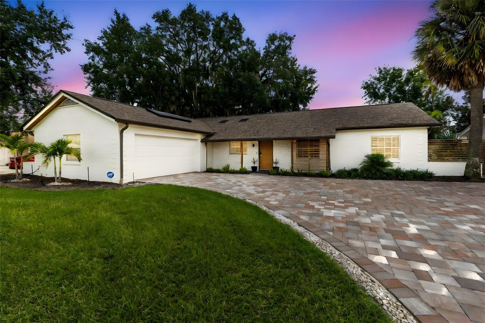 Welcome to a rare hidden gem in Orlando—tucked away on the canal off Clear Lake, the only place in the city where you can live on a skiable lake for under $800K. This home isn’t just about four walls, it’s about a lifestyle: boating, waterfront sunsets, mid-century modern design, and the kind of privacy and convenience you won’t find anywhere else while still being within City limits. Every inch of the home has been transformed. Outside, you’ll find a new paver driveway that wraps around both sides of the home and extends to the rear porch, framed by new flower beds, a modern front door, and fresh exterior paint. The entire exterior was redesigned into a clean mid-century modern look, with a new roof, skylights, seamless gutters, and insulated garage door. Your backyard is an entertainer’s dream, featuring a completely resurfaced pool and spa with a brand-new Rheem digital heat pump, plus a new wood dock with a 10,000-lb boat lift surrounded by composite decking—perfect for afternoons on the water. Step inside to an open floor plan where walls have been removed and wood beams installed to create flow and connection. The heart of the home is the fully gutted kitchen with new cabinets, quartz countertops, and top-of-the-line KitchenAid appliances, opening seamlessly into the living room. Natural light pours through new energy-efficient sliding glass doors, while fresh interior paint, new ceiling fans, recessed lighting, and custom blinds complete the airy vibe. Throughout, the sellers uncovered and restored the original terrazzo flooring, tying the home’s mid-century modern heritage to its new design. Additional features include a beach-themed mural in the dining room, a bonus room/office off the back porch, and upgrades like an ADT security system and smart thermostat for peace of mind. This home is completely move-in ready—no projects, no updates, no hassle. Just bring your boat, your friends, and your love for lakefront living.