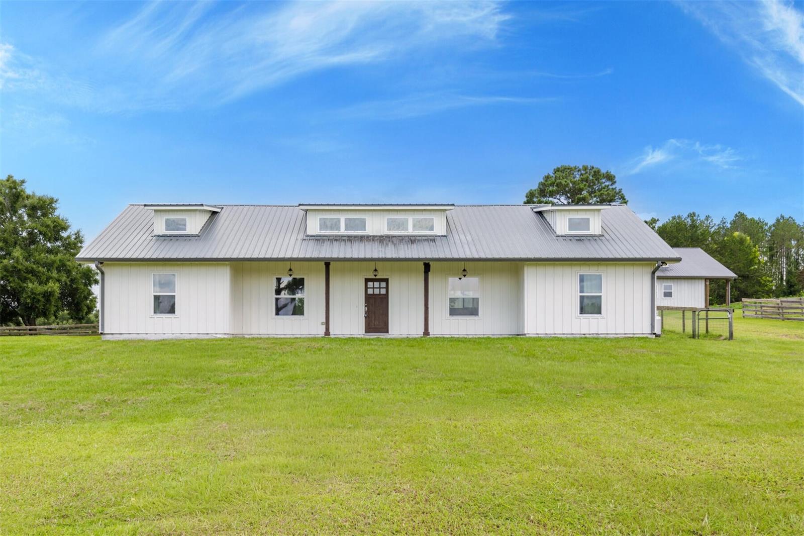 Bring Your Horses!
Welcome to this gorgeous 6.28-acre horse property in the coveted Shaw Farms Community — a rare find that truly won’t disappoint. Perched high on a hill, this 3-bedroom, 3-bath home offers sweeping views of the jumping course and potential dressage arena near the entrance. Enjoy endless sunsets from your front or back porch while watching your horses graze. Inside, every detail has been crafted with care. AquaGuard Performance Flooring is waterproof, pet-proof, and kid-proof. Soaring ceilings with exposed hardwood beams create a warm yet airy feel. The bright and open great room is perfect for families who want to stay connected, while the dining room features a one-of-a-kind chandelier that’s sure to spark conversation. The modern kitchen boasts endless counter space, perfect for entertaining, along with SMEG stainless steel appliances and abundant windows that frame breathtaking views. Private Primary Wing – The luxurious primary suite occupies its own entire wing of the home, with abundant natural light, an oversized walk-in closet and a spa-inspired marble bath, featuring endless customization potential. Each bathroom in the home is unique, with marble floors and counters and beautiful white tiled walls. The guest bedrooms each have their own en-suite baths for privacy and comfort. The fenced backyard features no-climb fencing, ideal for dogs of any size while keeping them safely away from the paddocks.
The Barn:
Designed with both beauty and functionality, the barn has three separate entries, with the main entry opening to six 12x12 stalls (one can be converted to a double stall for maternity). All stalls include automatic waterers and attached 12x12 turnouts. The barn also offers two tack/storage rooms and is plumbed for a future bathroom and laundry. High ceilings and spacious stalls create a comfortable environment for your horses. 52 Miles from the World Famous World Equestrian Center! Minutes to Downtown Alachua and Town of Tioga.