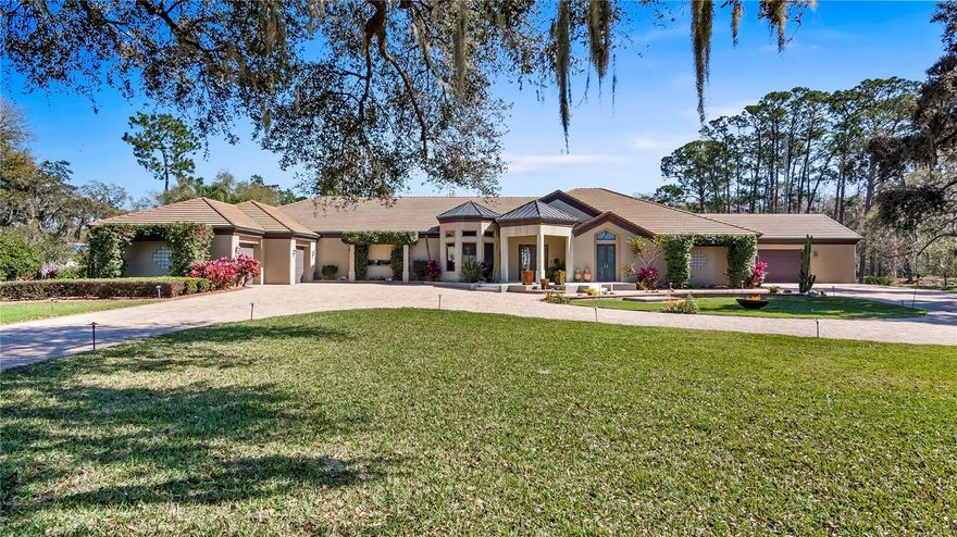 One or more photo(s) has been virtually staged. A Clermont Chain of Lakes direct waterfront home on over 6.5 acres with a gorgeous custom residence and no HOA. Waterski, wakeboard, kayak, fish, or just boat on 13 lakes— with Lake Louisa State Park just off your shoreline. Vacation every day in this fabulous property. Privacy is afforded behind the estate wall as the gate opens to reveal a concrete-paved, circular driveway around a stately old oak tree and manicured grounds, including a vineyard and seven producing citrus trees. The travertine front steps, accented by fountains and lighting, lead you through the custom Patina Copper front doors with views past the pool and rear yard to the lake through the 24-foot wall of sliding glass doors. This great room has 14-foot ceilings with specialty upgrades, including a cocina stone wall and custom lighting to accent tilework, ceiling coves, and niches. The music room has mahogany ceilings and fixed windows at the front of the home, making it an amazing home office, library, or reading space. The kitchen is phenomenal with panoramic views of the lake from almost every angle. Complete with Rutt custom-made cabinets around a large island with granite counters and seating, this is an incredible space for cooking, baking, and entertaining. Dacor double convection ovens plus a warming drawer and seven-burner cooktop, raised Bosch dishwasher, a Sub-Zero under-counter two-drawer refrigerator, a Sub-Zero refrigerator and freezer, and a Kohler cooking sink are more kitchen features. The butler's pantry off the dining room and the wet bar off the kitchen make entertaining easy. The family room boasts matching octagonal 14-foot mahogany ceilings, and the music room has an amazing gas (or wood-burning) fireplace accented by three cocina stone walls and seamless glass overlooking the gorgeous lanai and pool. The kitchen, bar area, and family rooms flow together for optimal everyday living or entertaining. The primary bedroom suite occupies one side of the home, and has a built-in California King bed, a sitting area with desk/library/TV niche, and views of the pool area. The bath has a Kohler ten-jet/waterfall shower, an adjacent Grohe shower, and an aquatic jetted tub. The walk-in closet also serves as a hurricane room, has extensive shelving and an island with drawer space. Just off the primary suite, another bedroom (currently being used as an exercise room) offers a full bath/steam shower and pool access. Another smaller bedroom has private access to an amazing screened-in butterfly garden lanai. A second ensuite bedroom has a great lake view, a large walk-in closet, direct access to the lanai and pool, and an amazing bath with a waterfall shower and a jetted tub. The separate in-law suite has a full bath, walk-in closet, and kitchenette with two large windows overlooking Lake Louisa. The lanai area is fantastic—lush tropical landscaping strategically placed so as not to obstruct the water views or the starry skies, and the 16,000-gallon pebble tec lagoon pool has a fabulous waterfall feature. Relax by the pool under the misting fans, grill at the Dacor electric grill or host a huge party or wedding here. There are five-car garages, an interior fire sprinkler system, Anderson windows and doors, and a full list of upgrades for you. Located within 45 minutes to Orlando International Airport, Universal, and Disney, but less than 15 minutes to shopping centers and department stores. See the interior/drone video and make your appointment today!