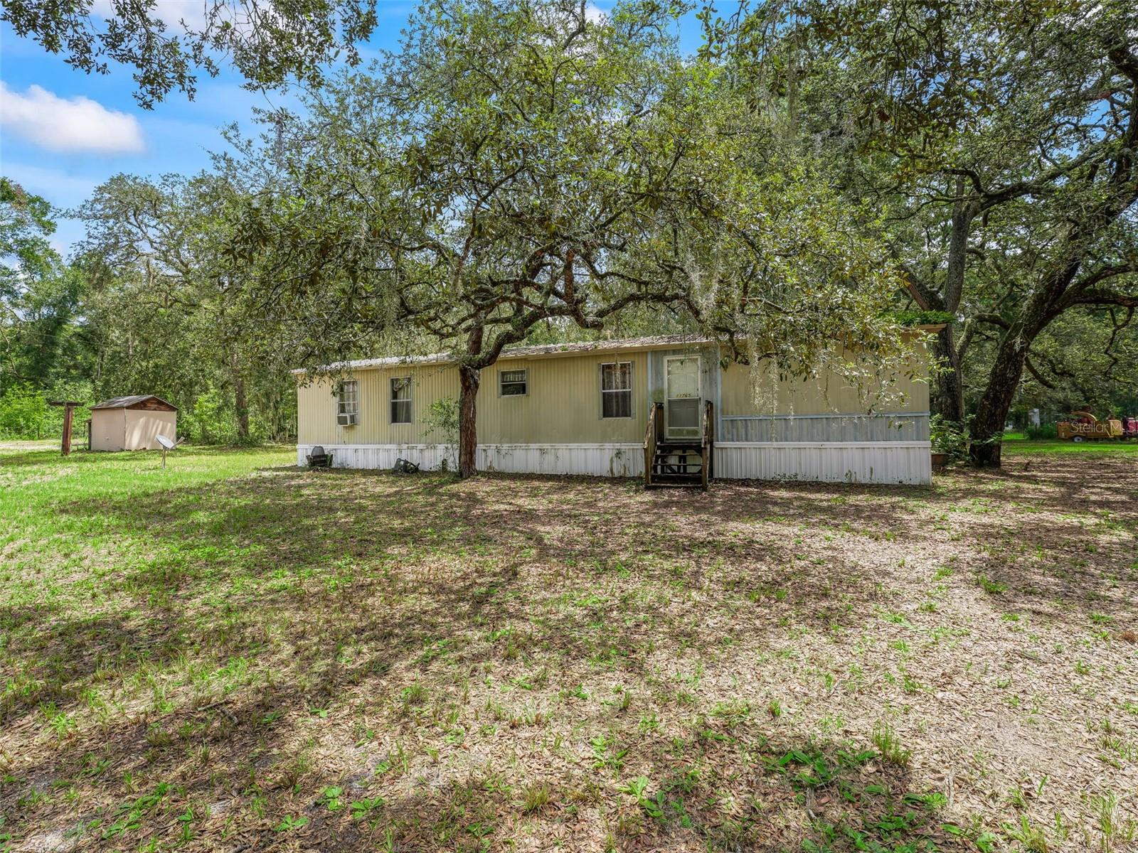 Escape the hustle and bustle while staying conveniently close to everything! This 2-bedroom, 2-bathroom mobile home sits on approximately 2.4 acres, offering plenty of space, privacy, and potential. The home features a desirable split floor plan, a spacious primary suite with dual sinks in the bathroom, and a 2-car carport for added convenience. Located within easy reach of Orlando, Tampa, Ocala, and The Villages, this property is just around 10 miles from grocery stores, restaurants, and medical facilities—giving you the best of both country living and city access. With a bit of TLC, this home could become your peaceful retreat or an excellent investment opportunity. Don’t miss your chance to own a slice of Florida with room to grow.