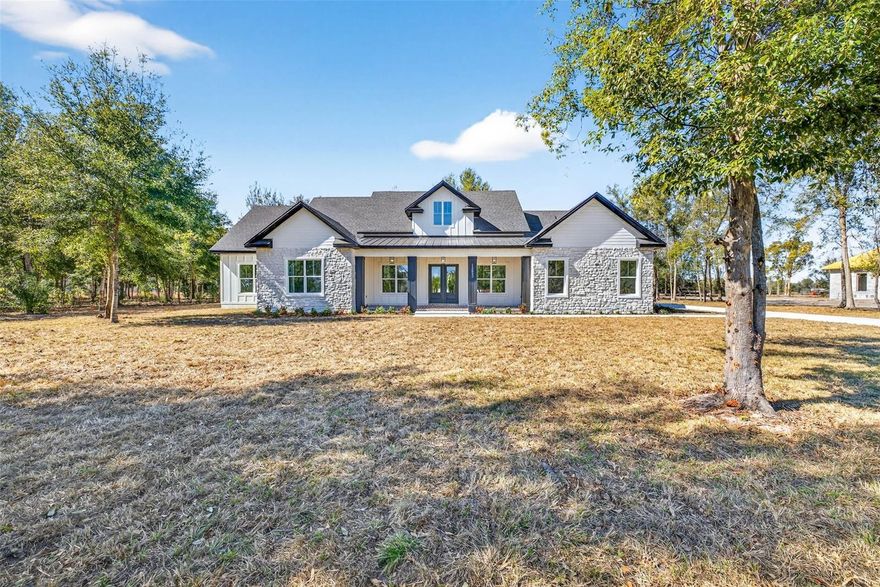 Welcome to this exceptional brand-new construction home offering 3,752 sqft of thoughtfully designed living space on just over an acre. This spacious floor plan includes 5 bedrooms, 4 1/2 bathrooms, and office, offering flexibility for multi-generational living, guests, or working from home. Every detail of this home reflects quality craftsmanship, intentional design, and modern luxury. The curb appeal sets the tone - striking stone accents, bold columns, a rich wood porch ceiling, and classic herringbone brick flooring create a warm yet sophisticated first impression. Inside, soaring vaulted ceilings with exposed wood beams anchor the living room, where a floor-to-ceiling stone fireplace and sliding glass doors connect indoor and outdoor living. The chef’s kitchen is both functional and stunning, featuring custom cabinetry, quartz countertops, built-in wall ovens, designer lighting, and an oversized island - all overlooking the main living area for effortless entertaining. A hidden walk-in pantry adds both convenience and style. The private primary suite is a true retreat, designed with both comfort and sophistication in mind. Offering generous space and features a stunning floor-to-ceiling stone fireplace, creating a warm focal point and inviting ambiance.Elegant French-style doors with frosted glass lead into the spa-inspired primary bath, where modern elegance meets thoughtful design. A freestanding soaking tub is perfectly positioned as a centerpiece, complemented by a dramatic oversized walk-in shower wrapped in designer tile and enclosed in frameless glass. Dual rainfall shower-heads, a handheld sprayer, and sleek matte black fixtures create a high-end, resort-style experience.The custom dual vanities provide abundant storage and counter space, blending warm wood tones with clean, contemporary finishes.From the bathroom, you’ll find not one — but two expansive walk-in closets featuring custom built-in shelving, drawers, and hanging space designed for optimal organization.Both closets conveniently connect directly to the oversized laundry room, creating a seamless and highly functional everyday flow. The laundry room is beautifully finished with extensive cabinetry, quartz counters, a utility sink, dedicated folding space, and room for additional storage — elevating even daily tasks with style and efficiency.This thoughtfully designed primary wing delivers privacy, luxury, and practical convenience all in one stunning space.Designed for true indoor-outdoor living, the expansive covered back porch extends your living space in the most impressive way. A rich tongue-and-groove wood ceiling with recessed lighting and dual ceiling fans creates warmth and architectural interest, while the wide-open layout offers ample room for dining, lounging, and entertaining.The fully equipped outdoor kitchen is a showstopper, featuring stacked stone detailing, granite countertops, a built-in grill with vent hood, beverage refrigerator, stainless storage cabinetry, and a sink for added convenience. Whether hosting weekend gatherings or enjoying quiet evenings at home, this space is designed for effortless entertaining year-round.Overlooking your large backyard offers both space and serenity — with endless potential to add a pool, detached structure, or custom outdoor oasis.This home masterfully blends luxury finishes, thoughtful design, and functional flow across, all set on over an acre, delivering privacy, space, and elevated living at its finest.