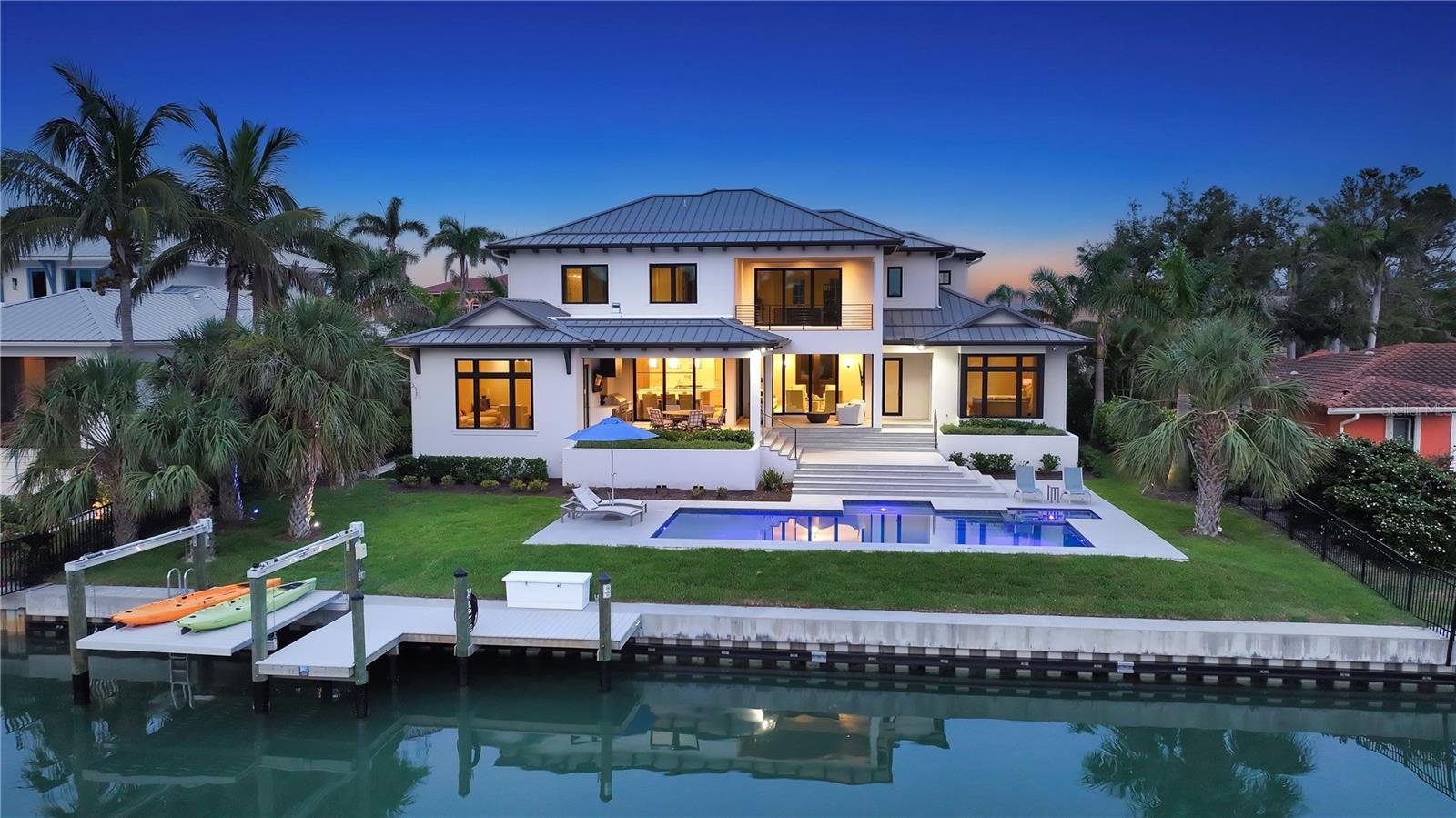 Built in 2022 by Voigt Brothers and designed by Arieno Custom Home Design, this new impeccable waterfront estate pairs sleek contemporary architecture with the comforts of elevated Bird Key living. Nestled along deep sailboat water just off Sarasota Bay, this Bird Key home spans over 4,700 square feet of beautifully finished interiors, seamlessly integrated with an expansive outdoor living experience. A pavered circular driveway framed by manicured landscaping welcomes you to this modern coastal residence. The elevated two-story design features a durable metal roof, impact-rated glass throughout, and an oversized two-car garage complete with epoxy flooring, mini-split A/C, storage, and elevator access. Inside, a blend of thoughtful engineering and elegant design unfolds—highlighted by solid hardwood floors, soaring 10’ and 12’ ceilings, Lutron-controlled lighting and shade systems, and walls of pocketing sliders that merge indoor and outdoor spaces with effortless grace. The heart of the home is a gourmet kitchen designed to both impress and perform. Anchored by a massive quartz-topped island, it features professional-grade Wolf appliances, hidden range hood, double built-in ovens, 6-burner gas Wolf cooktop with pot filler, and custom cabinetry offering abundant storage. A wine cooler with refrigerator drawers, prep sink, and dedicated Butler’s pantry with built-in desk enhance everyday functionality. This culinary hub flows into the dining room and great room, where a gas fireplace, tray ceiling, and custom floating shelves set a refined tone. The main-level primary suite offers a private retreat, with vaulted ceilings, its own dedicated laundry room, French door access to the terrace, a spa bath with soaking tub and rainfall walk-in shower, and a custom closet system designed to accommodate two wardrobes. Completing the main level is the office and impressive club room that offers additional lounge space with media potential, opening directly to the outdoor lounge for effortless entertaining. Upstairs, a loft-style family room currently serves as a fitness area, alongside three spacious guest suites with walk-in closets, a second laundry room, and a morning bar for added convenience. Take the elevator or ascend the bespoke staircase to access every corner of this thoughtfully designed home. Outside, two levels of resort-style entertaining spaces include a covered lanai with summer kitchen, electronic screens, and multiple seating areas. The heated pool and spa feature a sun shelf and tranquil waterfall. At the water’s edge, a new seawall supports a dock with four-post platform lift, offering direct access to the open waters of Sarasota Bay and beyond. Located in the sought-after Bird Key neighborhood, residents enjoy a private island lifestyle just minutes from downtown Sarasota, St. Armands Circle, and Lido Beach. Indulge in boutique shopping, fine dining, and the area’s renowned cultural scene including theaters, art galleries, and the marina. Optional membership to the Bird Key Yacht Club offers additional opportunities for boating, tennis, and social engagement. This is coastal living redefined—crafted with intention, and ready for your next chapter.