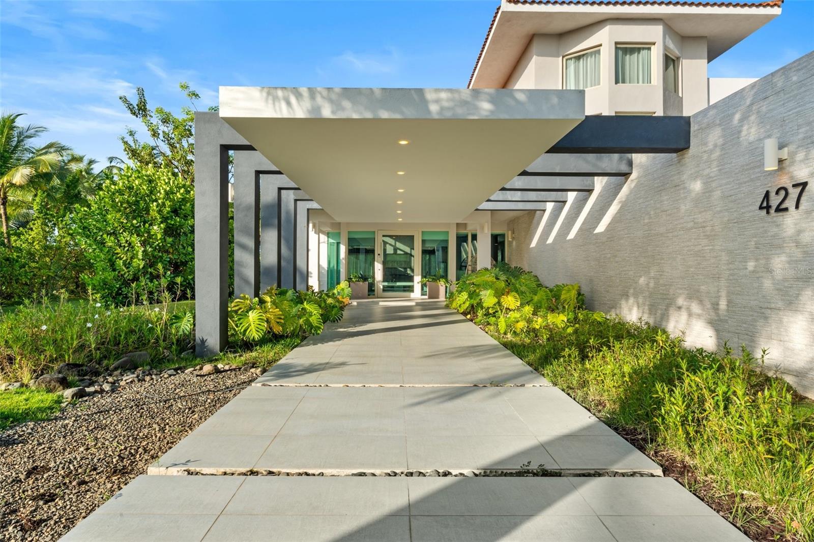 Located within the prestigious gates of Dorado Beach East, this modern and elegant multi-level residence sits on over 2,440 square meters of titled land—one of the largest lots in the community. Designed with style and functionality in mind, the home offers 5 bedrooms, 7 full bathrooms, 1 half bath, as well as a versatile bonus room that can serve as a sixth bedroom, office, media room, or guest space.
The third level features a private suite with a walk-in closet, en-suite bath, and access to a terrace area, with potential for conversion into additional outdoor living space. On the second floor, soaring ceilings and large windows create an airy feel, with multiple bedrooms and a show-stopping primary suite that opens to a private balcony with expansive views of the golf course and lake. The primary bath is a true retreat, featuring a soaking tub, walk-in shower, outdoor shower, double vanity, private water closet, and custom-designed his-and-hers walk-in closets.
The first floor offers an additional bedroom with a built-in closet and full bath, as well as a flexible bonus room with a bathroom conveniently located just across from it. A wine cellar, mini bar with kitchenette, and dining area with glass doors that open to the exterior provide ideal spaces for entertaining. A floating staircase adds architectural interest, and the 4-car garage provides ample storage and convenience.
Outdoors, the home’s generous lot includes a private pool overlooking the lush landscape, offering the perfect setting for relaxing or hosting. Set within a world-class golf community, the home is conveniently located near the South Gate, allowing easy access to enter and exit the neighborhood. Blending upscale finishes with open, livable spaces, this residence is ideal for both refined daily living and stylish entertaining.