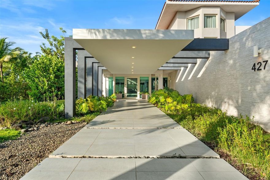 Located within the prestigious gates of Dorado Beach East, this modern and elegant multi-level residence sits on over 2,440 square meters of titled land—one of the largest lots in the community. Designed with style and functionality in mind, the home offers 5 bedrooms, 7 full bathrooms, 1 half bath, as well as a versatile bonus room that can serve as a sixth bedroom, office, media room, or guest space.

The third level features a private suite with a walk-in closet, en-suite bath, and access to a terrace area, with potential for conversion into additional outdoor living space. On the second floor, soaring ceilings and large windows create an airy feel, with multiple bedrooms and a show-stopping primary suite that opens to a private balcony with expansive views of the golf course and lake. The primary bath is a true retreat, featuring a soaking tub, walk-in shower, outdoor shower, double vanity, private water closet, and custom-designed his-and-hers walk-in closets.

The first floor offers an additional bedroom with a built-in closet and full bath, as well as a flexible bonus room with a bathroom conveniently located just across from it. A wine cellar, mini bar with kitchenette, and dining area with glass doors that open to the exterior provide ideal spaces for entertaining. A floating staircase adds architectural interest, and the 4-car garage provides ample storage and convenience.

Outdoors, the home’s generous lot includes a private pool overlooking the lush landscape, offering the perfect setting for relaxing or hosting. Set within a world-class golf community, the home is conveniently located near the South Gate, allowing easy access to enter and exit the neighborhood. Blending upscale finishes with open, livable spaces, this residence is ideal for both refined daily living and stylish entertaining.