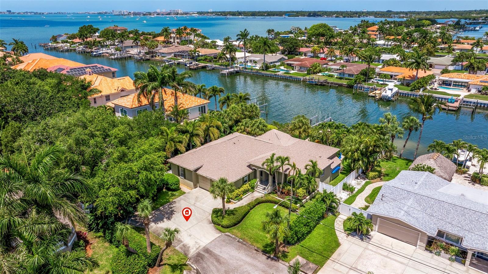 Here’s the ULTIMATE WATERFRONT RETREAT that will check off all your boxes:
1) PRIVATE, TROPICAL SETTING on an oversized waterfront lot with open access to Boca Ciega Bay
2) ONE-LEVEL COASTAL LIVING at 13-ft elevation with low-cost flood insurance
3) 95-FT OF LUSH WATERFRONT with natural mangroves, newly expanded dock and a 10,000-lb boat lift.
The original Builder’s primary residence, this stunning 5-bedroom, 3-bath home emits a sense of TIMELESS ELEGANCE combined with CONVENIENCE AND MODERN UPDATES where it matters most. QUALITY CONSTRUCTION AND PRIDE OF OWNERSHIP shine throughout the entire home and lush manicured grounds. As you enter the front foyer and step into the Great Room, you’ll be impressed by the 12-ft volume ceilings and the 5th bedroom utilized as a dedicated office featuring a rich wall of built-in cabinets and bookshelves. The cozy dining area adjacent to the Great Room is accented with a feature wall of driftwood grey shiplap, creating a friendly coastal ambiance for meals and entertaining. The open, split floor plan winds around to the Primary Suite boasting a beautiful arched triple window framing the backyard waterfront oasis. You will appreciate all the wonderful extras: Custom plantation shutters, crown moulding, built-in entertainment cabinets, newly updated Primary Retreat and ensuite bath with sleek light gray cabinetry, a vanity and a luxurious rain head shower system, and genuine Bamboo flooring in the secondary bedrooms. The heart of this home is a light and bright kitchen with high ceilings and an additional arched triple window showcasing the fabulous backyard amenities. An array of beachy white kitchen cabinets is complemented by the lovely soft tones of creamy Boticeno marble counter tops that surround a breakfast bar and cooking island. Two of the three additional bedrooms are connected by a freshly renovated bath featuring modern gray cabinets, BEAUTIFUL WHITE CALACATTA QUARTZ COUNTERTOPS with striking black veining, and a tub with a contemporary sliding glass enclosure.
As spectacular as the interior of this home is, the NATURAL WATERFRONT BEAUTY OF THE OUTDOOR GROUNDS is even more breathtaking! Boaters will appreciate the direct access to Boca Ciega Bay and the Gulf of Mexico, as well as the convenience of Maximo Marina positioned at the eastern end of the canal. Enjoy endless hours of sunbathing, swimming and entertaining on a sprawling, expansive pool deck with an oversize 43’ x 20’ pool and large sun shelf. Relax with a cup of coffee on your private dock and take in the morning sunrise … and be awed at sunset, watching the rainbow of colors in the evening Gulf sky. Follow the pavered pathway around the side of the property arched with a canopy of Areca, Date and Banana Palms past the trickling Italian Wall Fountain to your very own secluded putting green, shaded by stately oak trees. With a prime location just off the Pinellas Bayway via I-275, THIS WATERFRONT PARADISE is only a few minutes away from downtown St. Pete, our award-winning Gulf Beaches, Fort DeSoto Park, and a huge array of local shops and restaurants. Plus, you are only 25 minutes from Tampa International Airport! Your ULTIMATE COASTAL LIFESTYLE with luxury, comfort, leisure and convenience awaits you. YES, YOU CAN HAVE IT ALL!!