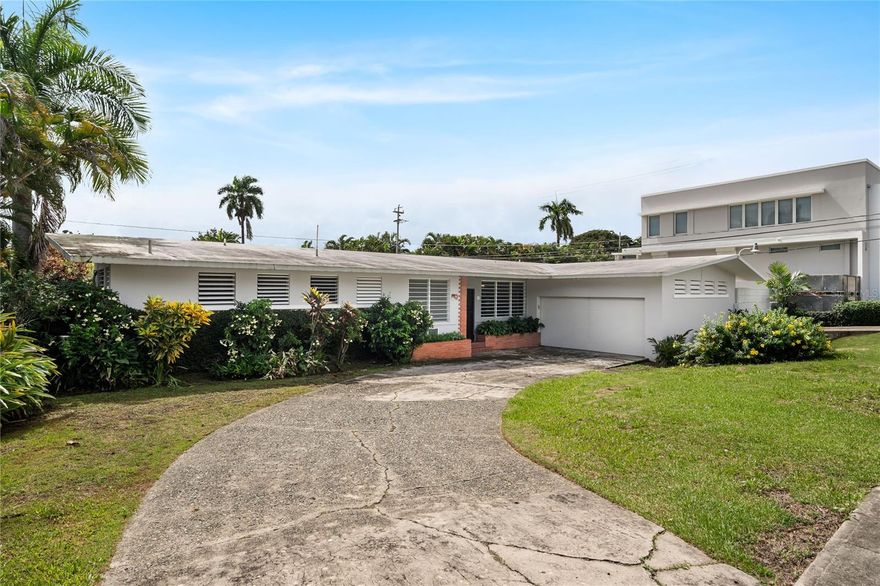 Experience the perfect blend of elegance, spaciousness, and an unbeatable location in this distinguished residence located in Garden Hills Norte, one of Guaynabo’s most exclusive, secure, and sought-after communities. Its serene atmosphere, wide streets, and controlled access create the ideal setting for a comfortable and stylish family life.
From the moment you enter, this property captivates with its classic architecture and four-sided gabled roofs reaching 12-foot-high ceilings, providing natural light, ventilation, and a remarkable sense of openness. Every detail has been carefully designed to bring functionality without sacrificing elegance, creating spaces that invite daily enjoyment.  
Layout and main features:
• Five spacious bedrooms, three of them with en-suite bathrooms, ensuring maximum comfort and privacy for every family member (4.5 bathrooms total).
• 2,770 square feet of construction on a 1,040.7 square meter lot, offering an excellent balance between indoor and outdoor living space.
• A modern and functional kitchen featuring granite countertops, ample storage, and an ideal layout for those who enjoy cooking or sharing family moments.
• A concrete terrace, perfect for social gatherings, barbecues, or simply relaxing at the end of the day while enjoying the tropical breeze.
• Double garage with driveway and an additional side garage, providing total parking capacity for up to four vehicles.
• Independent laundry area with extra storage space.
• Power generator and solar water heater, ensuring energy efficiency and peace of mind in case of unexpected outages.
Located in the heart of Guaynabo, this residence offers direct access to the best of urban and family living. Just minutes away are San Patricio Plaza, Suchville Plaza, and Garden Hills Plaza, where you can enjoy restaurants, boutiques, gyms, and essential services. It’s also steps from the exclusive Caparra Country Club and Torrimar Sports Complex, ideal for recreational, athletic, and social activities.
For families, the location couldn’t be more convenient — within close proximity to some of Puerto Rico’s most famous schools, including Maristas, Baldwin School, and Gersh Academy. It also offers quick access to the Tren Urbano station and main highways connecting to San Juan, Bayamón, and Dorado, making commuting simple and efficient.
This property is more than just a house — it’s a lifestyle. It offers the perfect balance of comfort, elegance, and convenience within a community where security and a sense of belonging are top priorities. Ideal for those seeking to elevate their quality of life, embrace tranquility, and enjoy everything Garden Hills Norte has to give