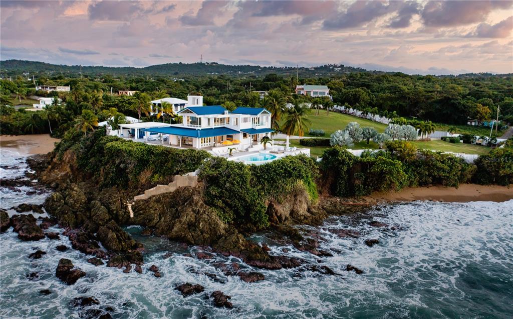 Serenity Point is a RARE and majestic oceanfront estate located cliffside in Monte Santo Playa on Vieques Island. Designed by the well known New York and San Juan prestigious firm Marvel Architects, the home is positioned to capture sunset views over El Yunque tropical rain forest. There is not a more sophisticated, unique, and private setting on the water in Puerto Rico. Vieques Island is 20 minutes from San Juan via commercial or private plane or land your helicopter on the sweeping lawn. Vieques is the new hot spot to escape to and truly find your Serenity!
Serenity Point offers extreme privacy on one acre with an access controlled gated entrance and winding, palm lined drive. The home features an infinity, cliffside swimming pool with a front row seat to the clear blue sea stretching out in front of you. Professionally landscaped with a variety of outdoor entertaining areas including a gas fire pit and featuring Italian designed furniture. Alfresco living is raised to an art form at Serenity Point! There is high speed internet throughout the property.
The front door opens to a custom furnished living room surrounded by glass with breathtaking ocean views. Luxury finishes throughout the home including a recessed Jean Paul Gautier for Roche Bobois furnished living room. Throughout the home there are high ceilings, air conditioning, a custom designed Nautilus shell inspired stairway, automatic Lutron shades throughout the home with additional blackout shades in the bedrooms, recessed lights, video security system, integrated Hue lighting system and a laundry with two sets of washer/dryers. Roche Bobois and Mitchell Gold furnishings throughout and carpets from ABC Carpet and Home.
The home features five bedrooms and five and one half bathrooms across multiple structures affording extreme privacy. Each bedroom offers stunning water views from the guest casita with en suite and kitchenette and a two bedroom apartment with an en suite and a full kitchen. All of the bedrooms have walk in closets.
The modern eat-in custom kitchen features abundant storage, quartz countertops, and a suite of high end appliances including GE Monogram refrigerator/freezer, oven and stove, and integrated dishwasher. There is a full bathroom off the kitchen with both having easy access to the pool area.
One of the secret surprises of this home is natural "grotto" salt water swimming pool accessed by a narrow, hidden stairway. There is beach access with the best snorkeling and diving on the island. The home has a back up power generator and back up cistern water storage. There are expansive water views from every room in the house and vantage point with photos unable to truly capture this one of a kind home. Serenity Point is turnkey and must be seen in person to experience the essence.
Serenity Point has been lovingly cared for and curated by it's owner and has never been a rental or AirBnB.
