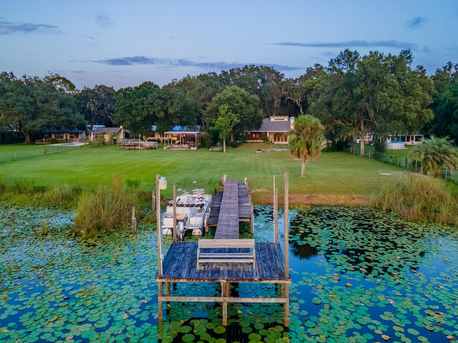 Situated on 2.19 acres with 200 feet of waterfront on Little Lake Kerr, this unique property offers spectacular sunsets, privacy, and room to entertain. The estate features both a custom-built main home (2005) and a guest home, perfect for multi-generational living or hosting extended family and friends.
The main home includes 3 bedrooms, 2 bathrooms, plus a half bath outside for lake and work days. With 1,761 sq ft under heat and air, the home features vaulted ceilings, abundant natural light, and an open floor plan. The custom kitchen includes cherry cabinets, granite countertops, double ovens, glass cooktop, double-drawer dishwasher, and large sink with bar area. The spacious primary suite (15’x19’) includes a walk-in closet and en suite with tiled walk-in shower, vanity, and private toilet area. Guest bedrooms share a Jack & Jill bath with tiled tub/shower combo. A wood-burning fireplace anchors the living room with lake views, while French doors open to a rear covered porch, fire pit, and landscaped backyard. Additional features include a 24’x12’ carport, laundry/utility room, and screened area off the living room.
Outdoor living shines with a 24’x24’ covered gazebo (power, lights, ceiling fans, and hot tub), above-ground pool with sun deck, large multi level dock for the boat and a concrete boat ramp.
The guest home (1974 mobile home with full-length addition) offers 1,344 sq ft, 2 bedrooms, 2 bathrooms, dining area, updated kitchen with range, refrigerator, island, custom cabinets with wood countertops, and a 46’x12’ living room with three large picture windows overlooking the lake. Several storage buildings are located between the two homes.
Surrounded by the Ocala National Forest, this property is minutes from the Salt Springs Recreation Area, Lake George, and the St. Johns River. The area offers endless opportunities for boating, fishing, hunting, hiking, and trail riding, with everyday conveniences just minutes away. Only 30 minutes to Ocala or Palatka.
This is a one-of-a-kind lakefront retreat combining privacy, modern updates, and multiple residences—perfect for year-round living or as a family getaway.