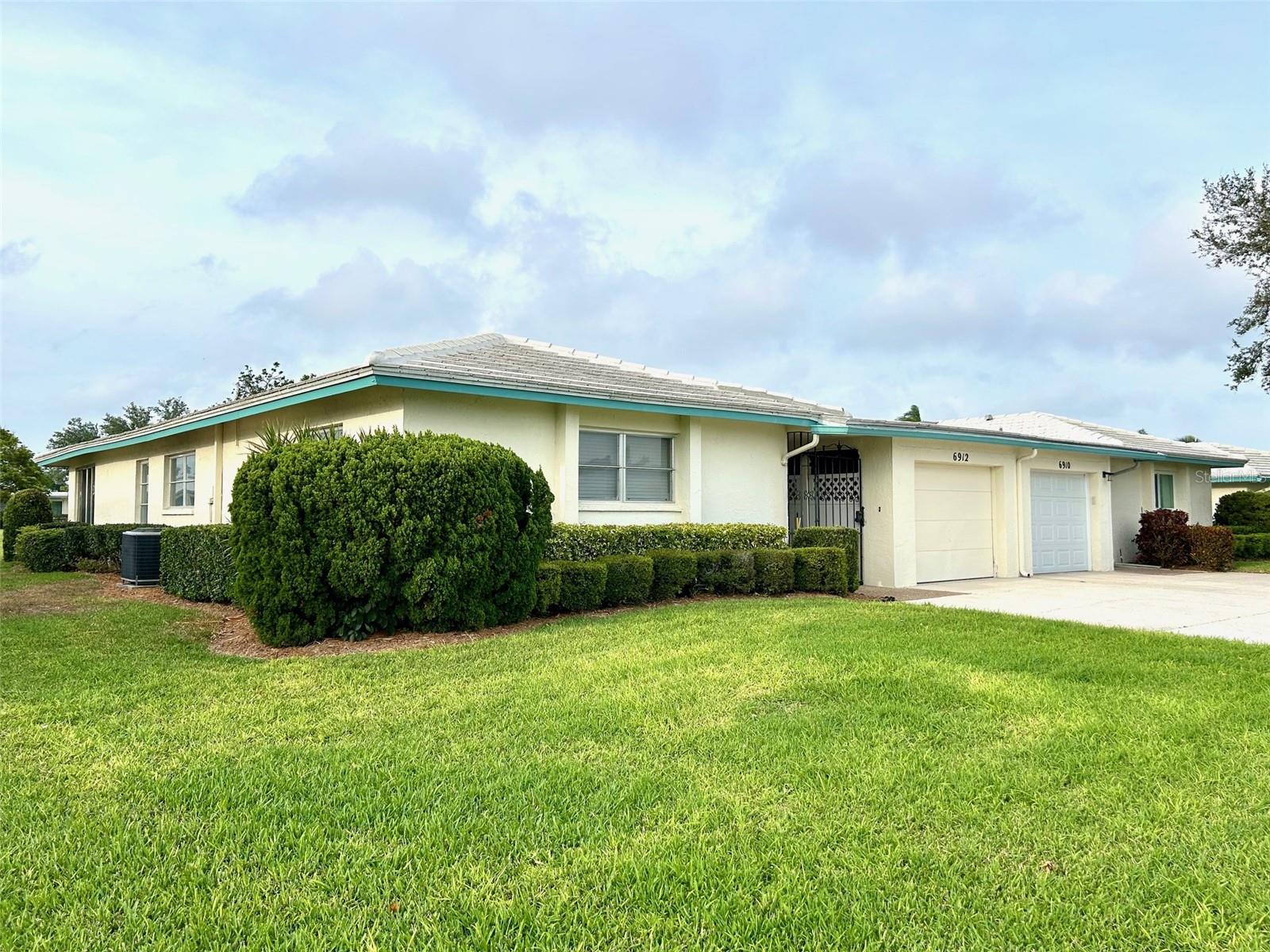 What a great place to come home to! This West Bradenton 55+ villa is located in the much-sought-after community of Village Green. This charming home is a short drive to the beautiful beaches on Anna Maria Island, Palma Sola Botanical Park, kayaking and hiking at Robinson Preserve, great offshore fishing, fine dining, trendy shopping, medical facilities, boating, golf courses, and the famous IMG Academy. Whatever your heart desires, you will find it here in this great location. You will love the open space floor plan with green views from your kitchen, living room and dining area. Savor your morning coffee in a very large Florida room with stunning views of beautifully manicured greenery complete with a walking trail. This unit has an extra-large driveway where you easily can park 4 cars. An attached one-car garage is a bonus—a convenience when bringing your groceries inside. Enjoy a new refrigerator, garbage disposal, outdoor shut off for water, a newer garage door opener, newer duct work and a newer hot water heater. The kitchen and bathrooms were recently remodeled with shaker wood cabinets and Formica counter tops that resemble granite (2022). Your quarterly condo association fees cover exterior painting, lawn care, irrigation, basic cable and internet, maintenance of the shuffleboard courts, heated pool maintenance, and insurance of the structural. Roof maintenance and replacement is the responsibility of each member. Social activities include happy hour on Thursdays at 4:00 pm in the pool area, where residents can bring a dish to share. The pool building is known as the Ramada, a hotspot for making new friends and catching up with the latest neighborhood news. Electrical outlets are available for hotplates. Social club members go out to eat once a month exploring new cuisines at local restaurants. The HOA annual fee of $100.00 supports neighborhood beautification programs. HOA contribution is optional but highly encouraged. A small pet is allowed with board approval.