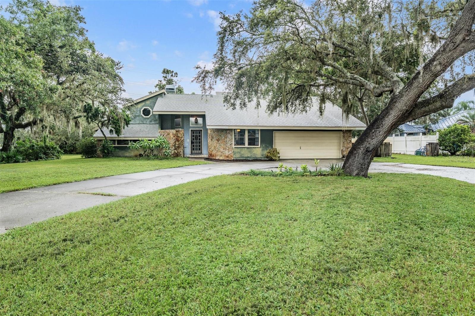 WOW, these opportunities don’t come around often. Nestled on over an acre of land in the highly sought after Oak Ridge community in Trinity, Florida, this spacious two-story POOL home offers nearly 2,500 sq. ft. of living space designed for comfort and entertaining in your own personal slice of heaven. Pulling up to this corner lot home, you are initially met by mature trees and beautifully landscaped yard with a large circular driveway, providing plenty of room for all your vehicles and toys. Step inside to an open floor plan with cathedral ceilings and a gorgeous stone fireplace in the family room. Look out the sliding glass doors to find a large patio with a cool deck and a sparkling clear pool and spa that overlooks a tranquil parklike backyard. Back inside, a dining room sits off the family room, along with a breakfast bar looking into the kitchen. The kitchen is spacious, with tons of counterspace and cabinets, newer stainless-steel appliances and undermount lighting. The primary suite is situated on the first floor with a huge bedroom, fireplace, cathedral ceilings, a private office space, and bathroom with a tiled, walk-in shower. A second bedroom and full bathroom round out the first floor. A spiral staircase leads to the second floor that includes a large loft area, a third bedroom with spacious closet and a third full, updated bathroom. The second floor also has a private, exterior entrance and staircase on the side of the garage. You’ll also find an indoor laundry/utility room and oversized two-car garage with lots of storage. The property is just over one acre and NOT in a flood zone. With a prime Trinity/New Port Richey location, convenient to shopping, dining, highly rated schools, award winning beaches and major roadways—this property offers both privacy and accessibility to all your daily needs. Hurry, schedule your private showing today!