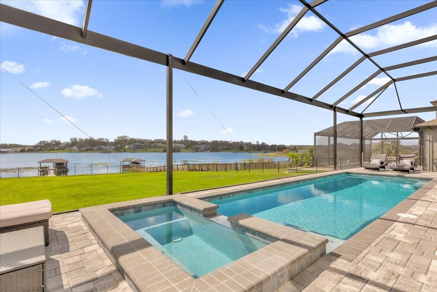 **HUGE PRICE REDUCTION** This luxurious two-story 2021 M/I Home is in the coveted John’s Lake Landing community. Set on the largest lot in the neighborhood, this property combines high-end upgrades and outdoor amenities, creating a perfect lakeside retreat. (To see the full video visit https://media.floridahomephoto.com/13016-Shady-Retreat-Loop/idx or click the link for the virtual tour!)

Upon entering, you are welcomed by 8 foot raised panel interior doors that emphasize the home’s grand feel. The open-concept kitchen features a large island with Pietra quartz countertops and solid hardwood cabinets, along with a Samsung Bespoke Refrigerator and a custom butler’s pantry with a built-in GE microwave. For added convenience, the kitchen includes a farmhouse sink, soft-close drawers, and a pot filler, ideal for meal preparation. A GE stainless steel double oven and dishwasher complete the upscale kitchen, which also features a walk-in pantry. The living spaces are adorned with custom light fixtures and indoor and outdoor fans, while the family room features a cozy electric fireplace and 85" Samsung TV. The primary suite is a true haven, with French doors opening to a private balcony overlooking the lake complete with swings and two oversized walk-in closets. The primary bathroom includes a dual sink vanity, a waterfall shower head with four additional MOEN jets, providing a spa-like experience. Each of the five bedrooms features its own walk-in closet, with an en suite bedroom offering stunning lake views. The laundry room is equipped with a Samsung washer and dryer, along with a drop-in sink for convenience. The home also includes comfort-height toilets with new toilet seats throughout. The south-facing backyard features a saltwater pool and spa with a pool heater, surrounded by a panoramic pool cage, offering uninterrupted views. For cozy evenings, the backyard also includes an outdoor stone firepit. A 10-zone irrigation system ensures the lush landscaping remains pristine year-round. The dock includes a 20' boat slip, a double jet ski slip, and has been upgraded with solar lighting along the walkway. The dock is equipped with electric and plumbing, perfect for those who love to spend time on the water. 

Additional features include a Wasatch floor safe, water filtration system with reverse osmosis, a 24-hour Safetouch Security system covering all entry points, driveway, and dock views, and floodlights at the rear of the house for added security. The home also features UV lighting in the HVAC system, energy-efficient windows, a 240-volt outlet in the garage for high-voltage equipment or an electric vehicle charger.

The property includes an expansive 25-car driveway and a 5-car garage, with each garage door built to custom height standards a foot higher than standard garage doors, accommodating large commercial vehicles, boats, or trucks. The landscaping features black rubber mulch, which can last up to 10 years. Home builder's 15-year Structural Warranty is also transferrable!

This home offers unparalleled luxury, security, and space, all in the serene John’s Lake Landing community while still being close to major highways, the best schools and restaurants, as well as amazing views of the Disney fireworks every night! Schedule your showing today!