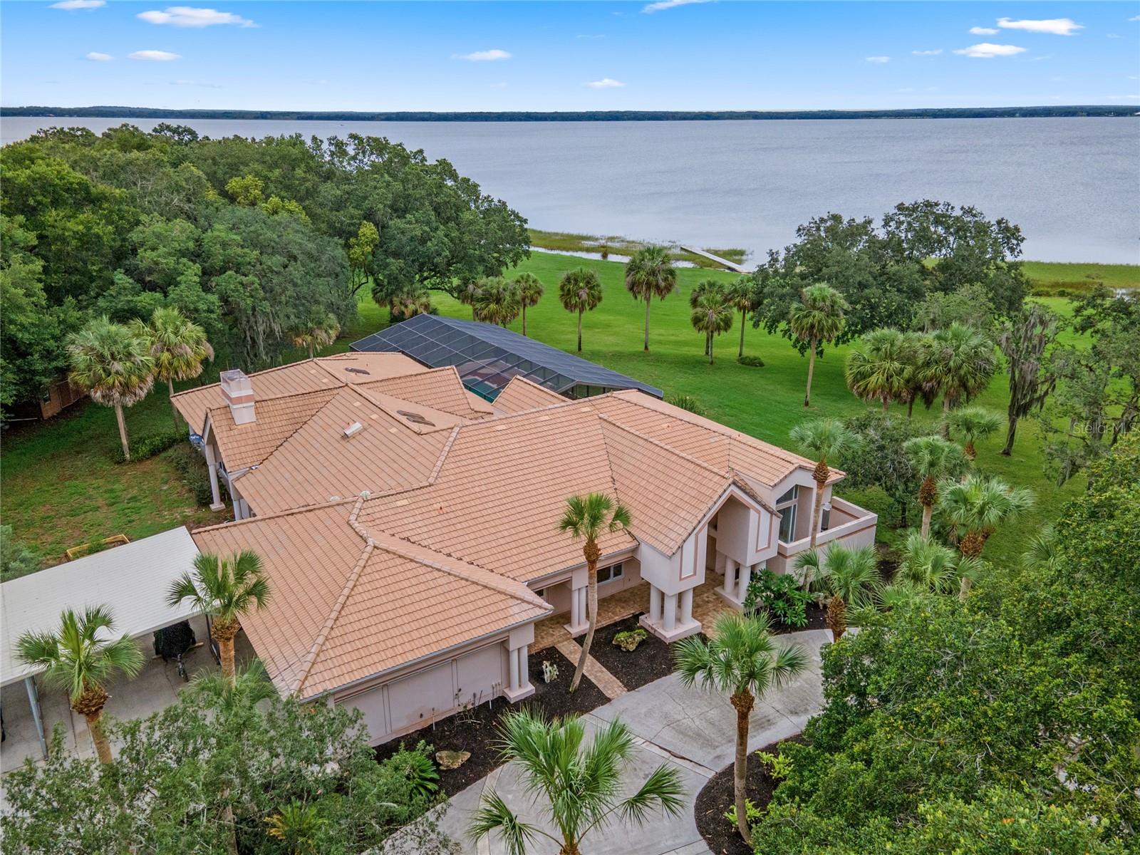 Welcome to an exceptional lakefront retreat offering tranquility, privacy, and breathtaking views in Grand Island, FL. Nestled on the serene shores of Lake Yale, this private oasis spans over 6 acres and boasts over 300 ft. of pristine lake frontage. As you approach through the tree-lined driveway, you'll be captivated by the sheer beauty of this magnificent home and its exquisite backdrop. Step inside and be greeted by its architectural brilliance. The dining and living rooms feature soaring ceilings, creating an airy and grand ambiance. Adorned with custom stained glass windows and built-ins, every corner of this home exudes elegance, and of course, the views from every window are simply mesmerizing. Prepare to be dazzled by the gourmet kitchen, showcasing a stunning granite center island and top-of-the-line appliances. With a wall oven, microwave, flat top stove, built-in Sub-Zero refrigerator, ample cabinets, a generous walk-in pantry, built-in desk area, and a charming breakfast nook overlooking the tranquil lake and pool, this kitchen is a true haven for culinary enthusiasts. The owner’s suite is a true sanctuary, featuring gleaming hardwood floors, three sets of French doors with Plantation shutters opening to the pool, and a large picture window framing the picturesque lake. With two custom walk-in closets and a master bath adorned with granite countertops, dual vanity sinks, a walk-in shower, and a jetted tub, this space is designed for relaxation and luxury. The family room offers a cozy and casual atmosphere, complete with hardwood floors, a fireplace, and built-in shelving, making it the perfect spot to unwind. Additionally, this remarkable home includes a spacious office with a private entrance, and a versatile studio/workshop that can easily accommodate fitness equipment or craft activities. The outdoor amenities are where this property truly impresses, with a stunning resort-style pool featuring a 50'+ lap lane, brick paver decking, and a heated spa, all enclosed within an expansive screen enclosure overlooking Lake Yale. This idyllic setting provides the ideal backdrop for hosting and entertaining, or just a quiet evening gazing at the view. Experience the ultimate in privacy without the constraints of an HOA, while embracing the true essence of the Florida lifestyle. Don't miss your chance to own this private paradise on the shores of Lake Yale. Schedule your showing today and make this exceptional lakefront home yours.