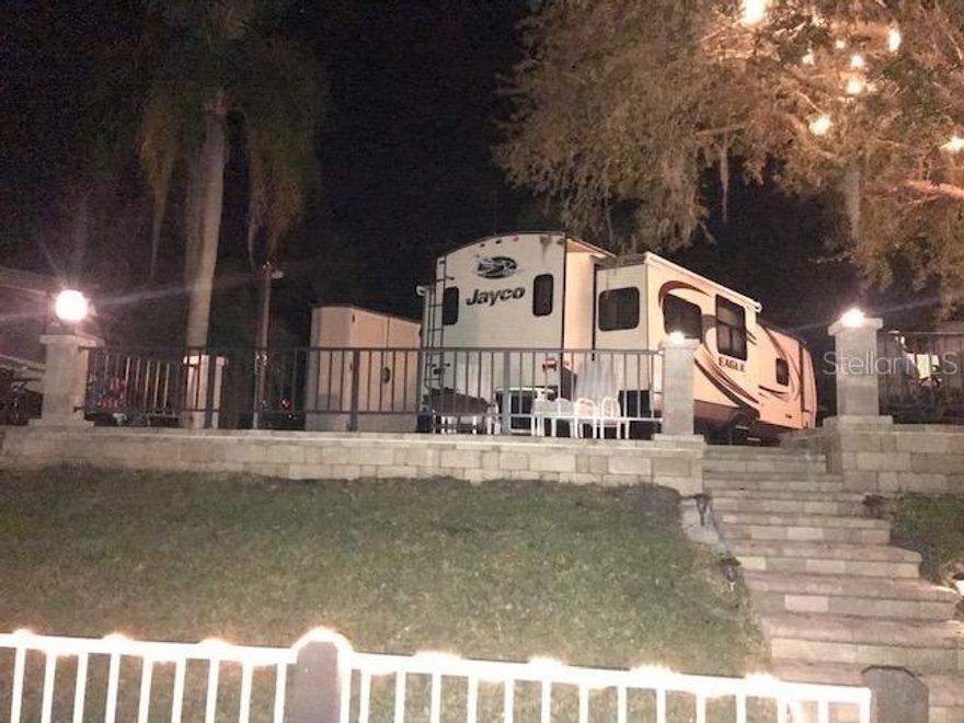 This RV Resort is special as is this opportunity to proudly own one of the nicest sites on the water which leads to the Kissimmee River and to Lake Kissimmee. This beautiful site is on the west side of the waterway which is considered the shady side. When at the Ranch in summertime you will understand why it is so important to have shade. Lot 436 has a very large oak tree that provides shade from 10:30 on when you are sitting on the elevated patio overlooking the waterway. The lot has been professionally built out to boast a paver stone wall that was necessary when the original footprint was lengthened approx. 6 ft to afford a much larger outside area. There is a 4 ft high wall which encloses the cooking area. There are 3 column posts with pineapple lights and lights strung high in the oak tree. The outside lights are on dimmers for a wonderful night ambience. Outside, you walk off the patio and down the steps to the dock and seawall. The sea wall is metal panels, not the old original wooden sea wall. there is electric and water at the dock. Its a great place to hang out and picnic, fish, etc.