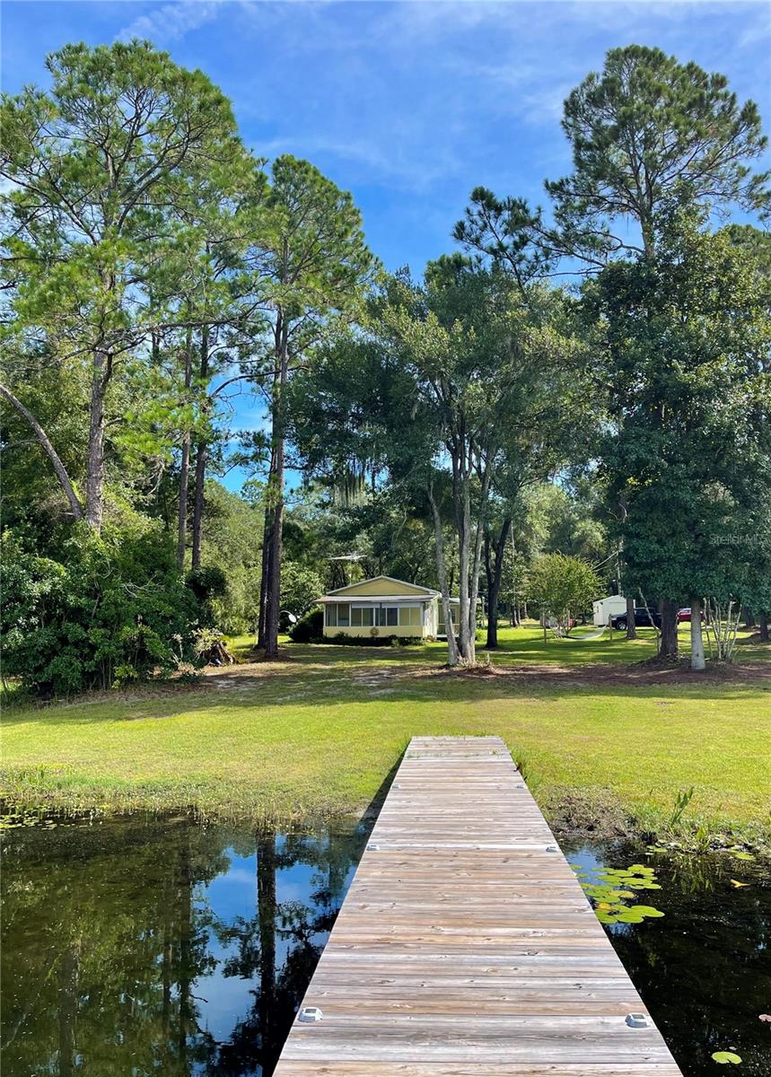 Crystal-clear waters of Lak-A-Wana Lake just a short drive from Gainesville/UF/Shands. This charming updated 2-bed, 1-bath cottage NOT IN A FLOOD ZONE offers breathtaking lake views, a peaceful shaded porch, and a spacious 3-acre lot. Metal roof, minisplit AC, septic, well, water filtration system, impact windows, flooring, wooden decks and cabinetry — all just 4 to 5 years old. Property includes a large chicken coop, two storage sheds, and even a golf cart for convenient rides around the grounds. Nature lovers will enjoy serene sunsets from the dock, abundant wildlife, and the fresh air of true lakeside living. Enjoy paved roads to your property & low Putnam County taxes. This property is perfect for gardening, raising chickens, goats, or simply going off the grid. Whether you're seeking a full-time residence or a weekend escape, this rare lakefront offering checks every box. Private lake access, separate meter for RV hookup, no HOA. Realtor-friendly and priced to sell! *********************** Important note: the LOT NEXT DOOR IS ALSO LISTED FOR SALE (MLS#A4661025): 101 Mcmeekin Rd, Hawthorne, Fl 32640. Both properties can be sold together. Imagine almost 5 acres (total) on your own lake! Lot next door is cleared & fenced with new septic and well. Call for details.