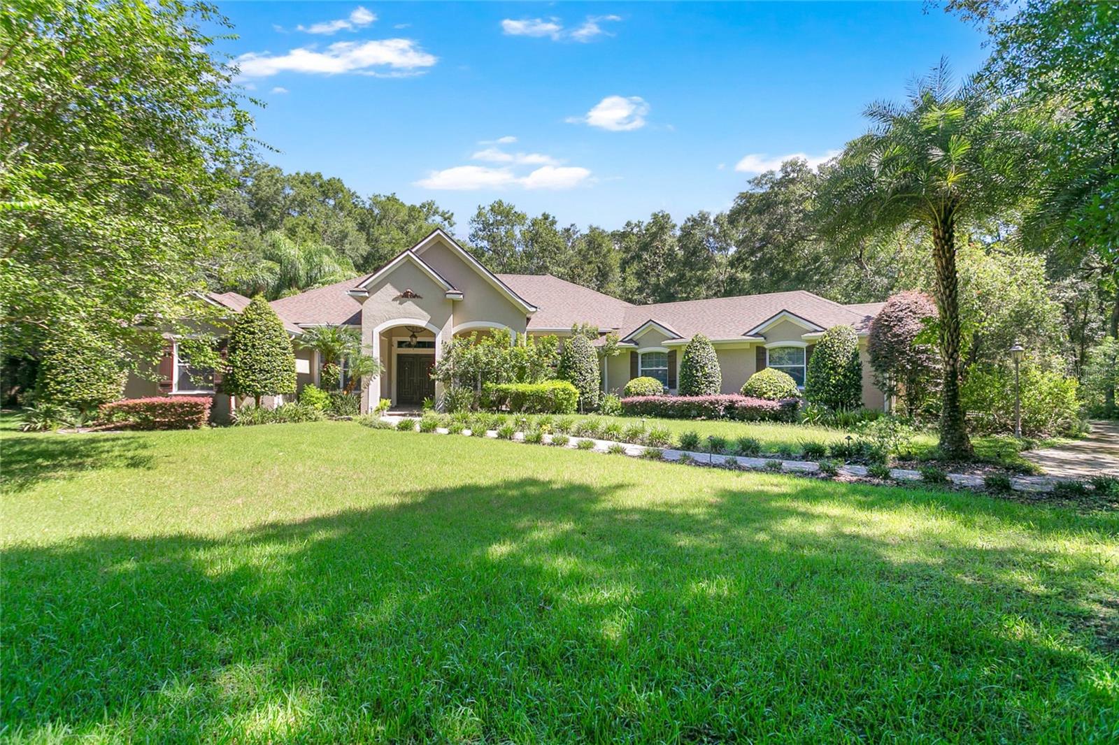 Welcome to your private Florida oasis! Nestled on 2.5 beautifully landscaped acres in a gated community in DeLand, this sprawling 3,443 sq ft single-story estate offers elegance, space, and privacy. With 5 bedrooms, 3.5 bathrooms, and a 3-car garage, this home is designed for those who love to entertain while enjoying the comforts of refined living.
Step inside to a thoughtful split-bedroom layout, soaring volume ceilings, and an inviting fireplace. Natural light fills the home through expansive windows and sliding glass doors, all enhanced by stylish shutters. The chef’s kitchen is the heart of the home, featuring gas cooking, a large center island with extra seating, elegant cabinetry, and high-end appliances. It flows seamlessly into the family room and breakfast nook, while formal living and dining areas provide additional space for hosting.
The luxurious owner’s suite is a retreat of its own, with two walk-in closets, a spa-like bathroom featuring a jetted tub and dual vanities, and private pool access for morning swims or evening relaxation. Additional highlights include a wet bar, inside laundry room, surround sound system, and tankless water heater.
Step outside to an entertainer’s paradise! The heated, screened-in saltwater pool and spa can be powered by gas, electric, or solar, and are complemented by a brand-new screen enclosure, pool pump, and outdoor kitchen with gas grill. A spacious rear screened patio and welcoming front porch extend your outdoor living options. Recent upgrades include a BRAND NEW ROOF with high-grade underlayment (potentially reducing insurance costs), new gutters with leaf guard, and a comprehensive security camera system.
Set in a tranquil gated community with low HOA fees, this property combines luxury living with peace of mind. With paved road access, well and septic utilities, and thoughtful details throughout, this home is a rare gem in Central Florida. Don’t miss your chance to call this estate your own!