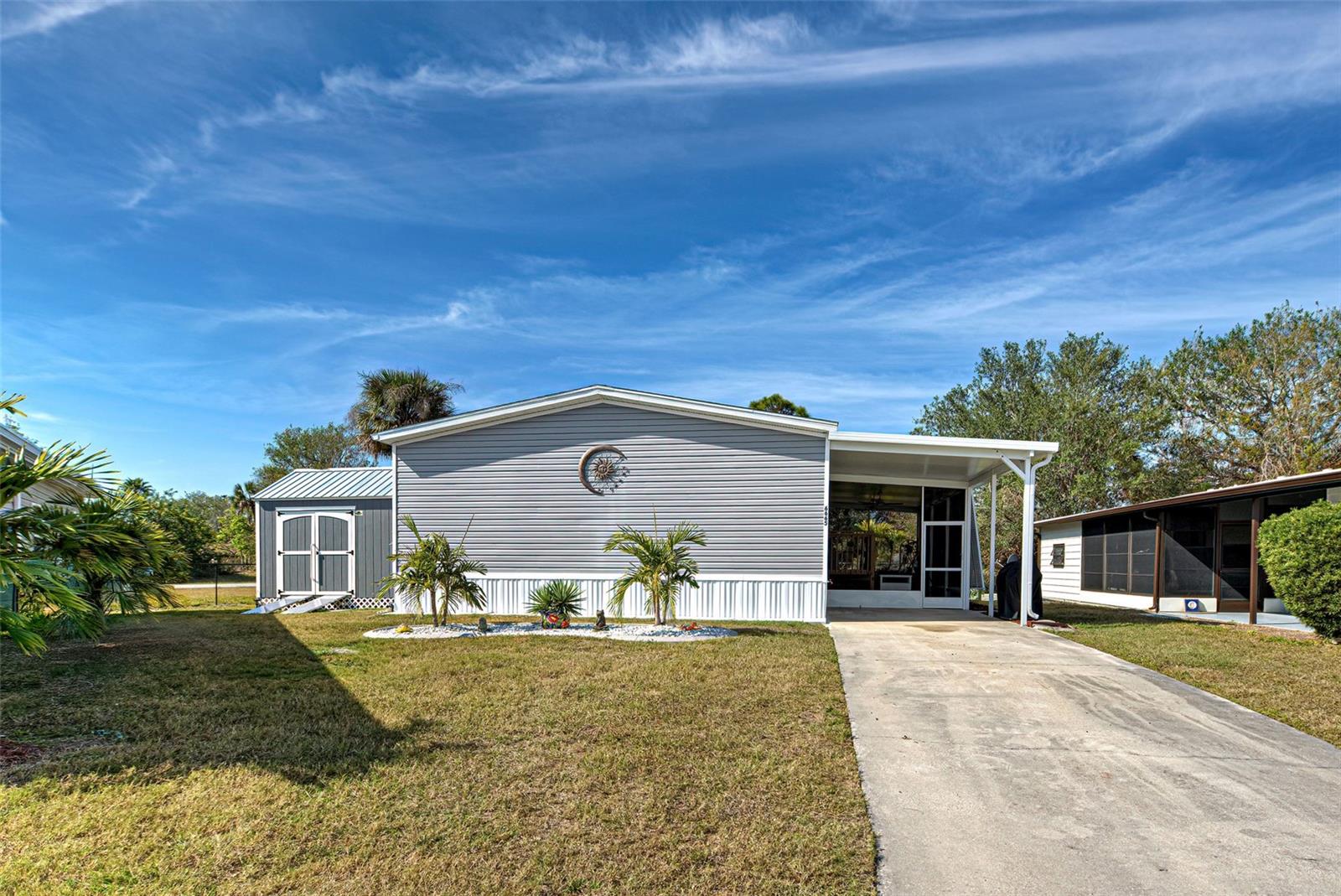 Welcome to fun and active Holiday Park in North Port Fl. A +55, Deed Restricted, Golf Cart friendly, manufactured/mobile home community. Community Clubhouse and 2 heated Pools. NO LOT RENTAL. YOU OWN THE LAND. This home is located in the PET SECTION. Presenting this sleek and modern, 2023, 1469 sq. Ft., 3/Bedroom, 2/Bath, w/Carport Lanai and Carport. One more time this is a 2023! Situated in a cul-de-sac on a nice sized lot. Being sold partially furnished. Floor plan is both contemporary, w/it's Open Floor plan, and unified w/attractive luxury vinyl flooring throughout. Great room, dining area and kitchen exemplify these points. Primary Bedroom/En-Suite are separate from the other 2 bedrooms. Allowing for privacy when having guests. En-suite is a nice size and includes a closet/storage area. 2nd and 3rd Bedroom's share guest bath. Both have walk-in closets. Oops let’s not forget the inside utility/laundry room w/extra cabinets. Exterior has not been ignored. HANDSOME AND FUNCTIONAL BAHAMA SHUTTERS($7k) on windows and the carport lanai. They add that “FLORIDA VIBE’. An excellent addition to this property is the 10x12 Workshop/Shed ($7,200). Yes, it has power. Handy Jacks and Jill’s will love it. Holiday Park offers so many activities and amenities. Clubhouse and 2/heated pools, tennis, pickleball, shuffleboard, fitness, library and more. The maintenance fee (Special Community District Fee) is included in the annual tax bill for your property. Holiday Park is located off US 41. It’s a short drive to shopping and restaurants. BEAUTIFUL DAYS, BEAUTIFUL NIGHTS, BEAUTIFUL FLORIDA!