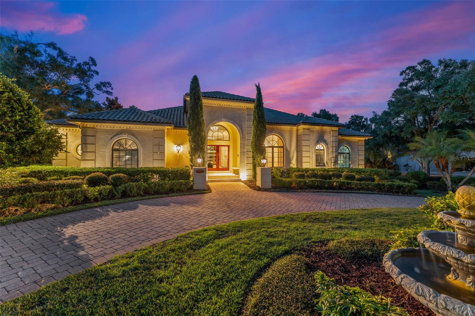 Nestled within the gates of the renowned Isleworth Golf & Country Club, this beautiful four-bedroom estate offers nearly 5,000 square feet and showcases an elegant transitional style. The main level welcomes you with gracious formal living and dining rooms, each crowned with sparkling chandeliers and framed by oversized windows that capture elevated views of the resort-style pool and spa below. Travertine floors flow seamlessly into the gourmet kitchen appointed with stainless steel appliances, a sunlit casual dining space, and direct access to both the intimate family room and an outdoor balcony for effortless indoor-outdoor living. Also on the primary level, the serene master suite offers a separate access to the terrace along with a luxuriously updated bath, and dual closets. Completing the primary level is a richly detailed wood-paneled office and a well-appointed laundry room, adding both warmth and function. The home’s thoughtful layout places the secondary bedrooms on the lower level, ensuring privacy and comfort for family or guests. Here, glass doors open to the multi-level terrace that gracefully surrounds the sparkling pool and spa, featuring generous deck space for year-round lounging and entertaining under the Florida sun. Offering an exceptional combination of timeless design, resort-inspired grounds, and a premier location within the gates, this remarkable residence is truly a sanctuary to call home.