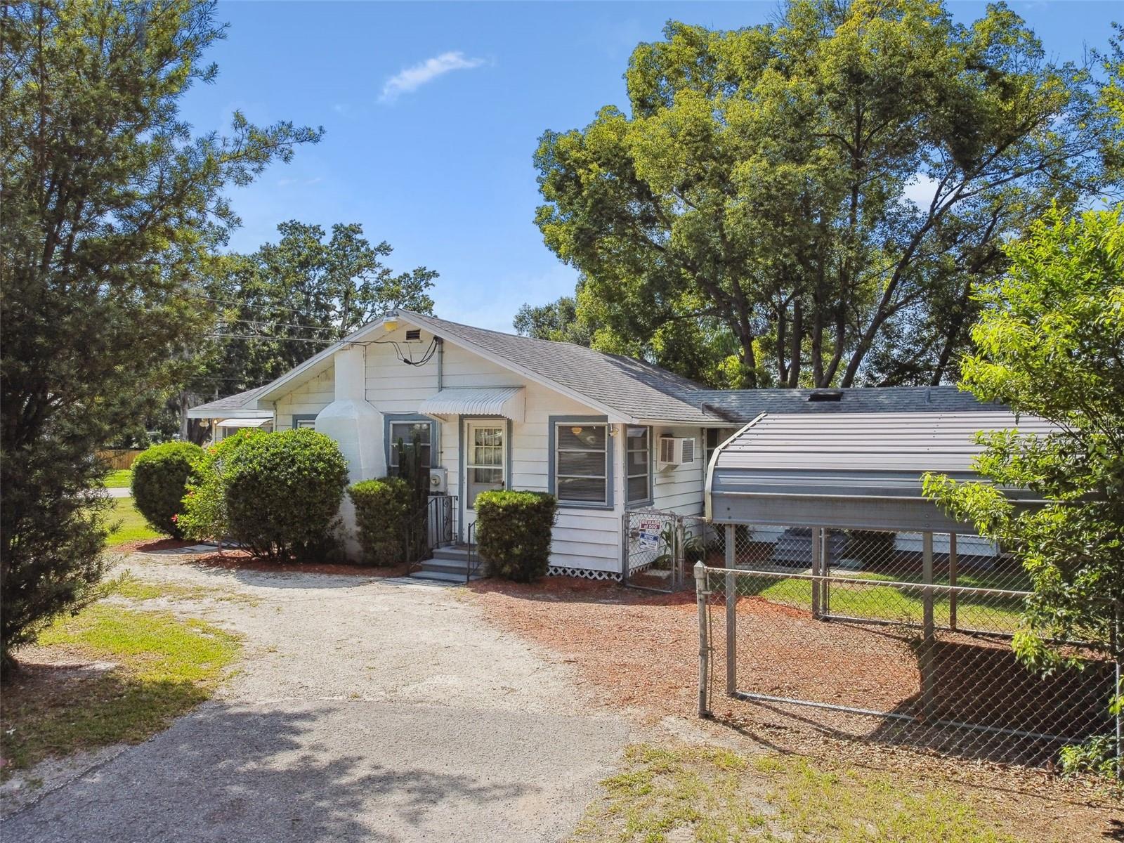 Charming and updated home just blocks from Historic Downtown Zephyrhills. Situated on a spacious lot with mature trees providing ample shade, this property features metal siding, a fully fenced yard, a detached carport, a wrap-around driveway, and a storage shed for added convenience. Inside, enjoy peace of mind with major updates including 200 amp electric service, assorted new wiring, a new small water heater plus wiring for a 30-gallon upgrade, a new HVAC system (2021) with 4 mini splits. New PVC coming into the home, which features all copper plumbing. New deep kitchen sinks & dishwasher. The kitchen boasts a new sink and faucet, an electric double oven (3–4 years old), and a new propane cooktop. Additional updates include newer toilets and modern faucets throughout. Roof is approximately 8–10 years old. While currently roofed over, the property also features a fireplace. Enjoy the small-town charm of Zephyrhills with walkable access to shops, restaurants, parks, and community events while still having the space and privacy of a generous lot.