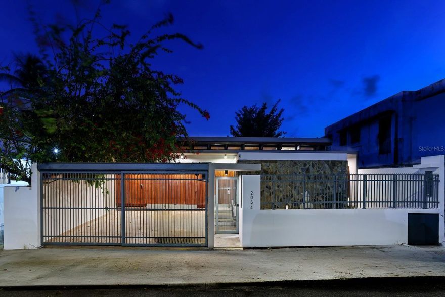 Architectural Masterpiece in the Beachside Gated Community of Ocean Park | Welcome to 2054 Calle España, an extraordinary residence where design, security, and innovation converge. Originally built in 2001 and inspired by the timeless architectural philosophy of Frank Lloyd Wright, this one of a kind home seamlessly blends natural elements with modern luxury. Thoughtfully remodeled, it stands as one of the most unique and secure homes in all of Puerto Rico. Bathed in natural light from above and below, the home features distinctive skylights and floor level windows that accentuate its open, organic feel. Locally sourced wood accents, natural stone floors, and textured exterior walls echo the harmony between nature and architecture. Fortified with new triple pane break resistant glass throughout the entire house in 2024, this provides even more peace of mind in the gated community of Ocean Park. Triple pane glass additionally reduces outside noise by over 30 decibels, making the interior a true sanctuary. Built to endure, it also provides exceptional hurricane resilience above and beyond traditional hurricane resistant glass. Multiple entry points are equipped with state of the art biometric access systems including fingerprint, passcode, facial recognition, and smartphone connectivity. Inside, no detail has been spared: Fulgor Milano kitchen appliances, white quartz countertops, elegant wallpaper finishes, designer sinks, reverse osmosis drinking water system plus whole-home water filtration, remote controlled blackout curtains in all bedrooms and living room, Midea air conditioning systems and Ring security cameras operable from anywhere in the world, and custom wood lighting throughout including a floating canoe light in the dining area paying tribute to Puerto Rico’s cultural heritage. Offering approximately 2,000 sq ft of refined interior space and over 3,000 sq ft of inviting exterior space, the home includes 3 bedrooms and 2.5 bathrooms. Indoor/outdoor living is enhanced by three large sliding doors in the living room, two in the hallway, and two more in the master suite, blurring the line between interior comfort and lush outdoor surroundings. The master suite features dual walk in closets, dual vanities, and dual rainfall showers. A guest bedroom with both interior and exterior access adds privacy and flexibility, while a third bedroom doubles as an office with a built in queen sized Murphy’s bed and generous storage. Outside there is: a heated salt water pool with multi colored lighting, a propane generator with an additional noise dampening box, a large water cistern on the roof, a Tesla vehicle charger, remote controlled parking gates, and an additional spacious storage unit accessible outside. The house is being sold furnished and the closing can happen as early as December 31st 2025.