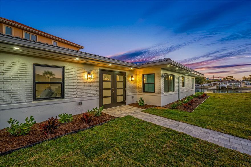One or more photo(s) has been virtually staged. 82 ft. of WATERFRONT SAILBOAT WATER. CLOSE TO THE BEACH on a corner on a quiet Cul-de Sac. Experience luxury living and stunning water views in this completely renovated 3 bedroom, 3 bathroom waterfront oasis. Every detail has been thoughtfully designed and upgraded from top to bottom, delivering a move-in ready home that blends modern elegance with effortless coastal charm
From the moment you arrive, you’ll be drawn in by the pristine curb appeal. Step inside to an open-concept living area where sun-drenched interiors and clean lines set the tone. The living room centers around a panoramic sliding glass door wall that frames glistening water vistas.The adjacent dining space comfortably seats family and guests, with designer lighting and water-inspired accents that create a coastal-modern atmosphere.The chef’s kitchen is a masterpiece of form and function, featuring top-tier materials and stainless steel luxury appliances. Quartz countertops, a substantial 10 ft island, with seating and custom cabinetry provide ample storage and prep space. A sleek backsplash, premium faucet, and custom lighting elevate everyday cooking into an experience.Retreat to the primary suite, a serene sanctuary overlooking the water and glass sliding doors opening to the pavered deck. The spa-inspired ensuite is appointed with a glass enclosed shower, dual vanities with gorgeous lighting, and designer hardware. Two additional bedrooms each offer generous closets and easy access to full baths, one of which doubles as a stylish guest bath with premium finishes. Large walk-in closet. No detail has been overlooked in the renovation. The home features a tile roof, updated electrical and plumbing, New Hvac, New waterheater, Hurricane windows and doors, including sliding glass doors leading to the inviting pavered deck by the water.Luxury finishes include wide-plank LVP floors, LED recessed lighting.An entertainer’s dream, the backyard is a waterfront haven with direct access to the water, a stone-paved terrace, and a low-maintenance landscaped lawn. Composite dock invites boating, kayaking, paddleboarding, fishing etc, newer seawall provides peace of mind. Enjoy your morning coffee or evening cocktail watching the sun set over the Gulf. This tropical oasis enables seamless outdoor gatherings for Family and Friends.Additional features include a two-car garage and ample driveway parking. The property is ideally positioned to enjoy an easy stroll to the sugary white sands of St Pete Beach nearby dining, boutique shopping while offering quick access to major highways for an easy commutes.This completely renovated waterfront home embodies luxury, comfort, and the essence of waterfront living. It’s not just a home; it’s a lifestyle upgrade—ready for new owners to move in, unpack, and start living the dream. Schedule your private showing today to experience the refined craftsmanship and the spectacular water views that set this property apart.