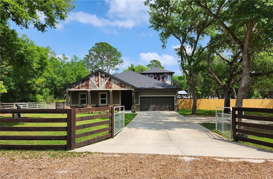 Modern Country Living - No HOA! Welcome home to this exceptional custom-built Craftsman-style ranch home nestled on a private almost acre lot. Designed for both comfort and entertaining, this spacious home features 4 generously sized bedrooms, 2 full bathrooms, 2 half bathrooms, plus a finished 5th bedroom/bonus room offering flexible space for a home office, gym, or media room. Newly built in 2022, this thoughtfully designed home blends exceptional craftsmanship with modern comfort and thoughtful design — all with no HOA restrictions. From the moment you arrive, you’ll notice the curb appeal —Step inside to an open floor plan with 10ft ceilings, 8ft doors all designed for easy living The heart of the home is the stunning kitchen made with entertaining in mind! Soft close maple cabinetry, abundant storage, a huge island perfect for gathering, granite countertops, walk-in pantry with custom wood built-ins and Samsung stainless steel appliances - Details that elevate everyday living. The spacious living room features a tray ceiling and centers around a wood-burning fireplace that flows seamlessly into the kitchen and dining area. The split-bedroom layout offers privacy, with the generously sized primary suite tucked away on one side of the home. The primary suite bath is designed with accessibility in mind, offering zero-entry access to the generously sized tiled shower ensuring comfort and ease for all stages of life. Large master bedroom closet with custom built-ins. Upgraded lighting fixtures, wooden window shutters and custom details throughout the home add warmth and sophistication to every space. On the opposite side of the home, you’ll find three additional bedrooms, custom built-in closets and a shared hall bath. While the upstairs features a fully finished fifth bedroom/bonus room with its own bath and closet — perfect for guests, teens, or a private retreat. Stained concrete flooring runs through-out the main living areas,ensuring hassle-free care with plank flooring in the bonus room and carpeted bedrooms for comfort. Need a place to store your toys. Bring them all! The private fully fenced backyard is every man's dream with a large 5 stall pole barn, double gates and a 10x16 shed. Separate side yard play area just for the fur babies. Additional features include: Front and rear covered porches, Low-E insulated windows and doors. Modern high speed connectivity with a dedicated internet line. Whole house generator plug with 50-amp breaker - 30 and 50 amp RV plugs. Overhead garage storage racks for additional storage. ADT security system with infrared cameras. Drive-thru driveway with solar powered double gates. Private well with iron breaker for trouble free water. Front and rear 4-zone sprinkler system. Ideally located just one minute from the boat ramp/boat slips to the Ocklawaha river, silver springs and the Harris Chain of Lakes makes this the ideal location for boating enthusiasts. Conveniently located 15 minutes to Eaton's beach and just 20 min to shopping and dining in the Villages, Eustis and Mount Dora. If you’ve been looking for newer construction, acreage, privacy, and a modern style — this one is sure to check every box!
