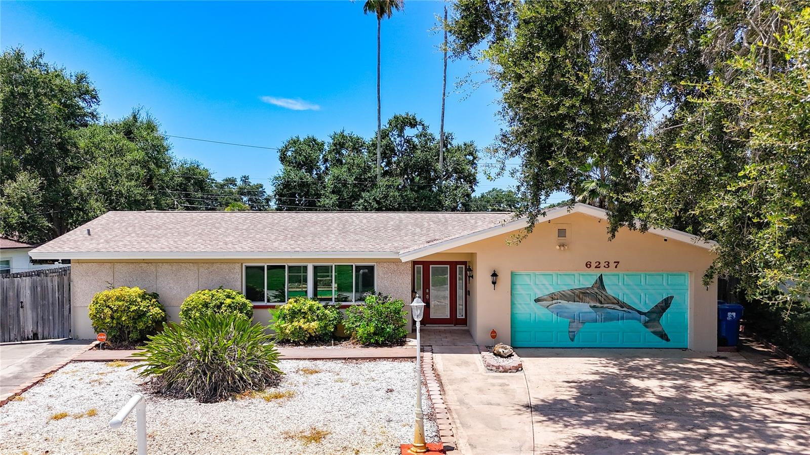 This charming one story split floor plan offers 4 bedrooms, 3 baths and is located in one of St. Petersburg’s most beautiful neighborhoods, West Wedgewood Park. You will find not only is the house spacious but it sits on a large lot just a short drive to the water, parks, shopping and more. The exterior of this home exudes privacy and stability. Upon approaching you will notice two long and large drive ways up to this concrete block construction home with an oversized two car garage. This home is enhanced by the house decor and beautiful curb appeal. This house stands out on the block with a custom artist rendition painting on the garage door. The front yard has very low maintenance landscaping witch is great for the Florida heat. The home has so many custom designs, each room is a treat. Upon entering, you are greeted with beautiful wood work in the foyer area and custom wall décor. The living room is a combination with the dining room, which is great for entertaining. This living room area is full of natural light from the gorgeous storm and wind impact windows. This living room dining room combo has beautiful parquet flooring that is easy cleaning. The owner’s suite is a treat in itself. It features a large walk-in closet with custom wood work and shelving. Along with a vanity area directly across from your en-suite. This owner’s suite also has beautiful large windows and a sliding glass door that leads right out into the pool area. The kitchen has well-made real wood cabinets, with lots of cabinet space, pantry and double sink. You will enjoy the fact that the kitchen is open to both the dining room and family room, as well as views of the pool. You have three access points to the pool area. So no shortage of being able to get to the fun in the sun. One bedroom is already set up for an office space with custom cabinetry and a Jack and Jill bathroom with stand up shower. All windows and sliding glass doors are impact-resistant or hurricane windows, combine with a heavy-duty window frame with impact-resistant glass. These windows are designed to not only to withstand high pressures during hurricanes but also to protect your home from flying debris. T