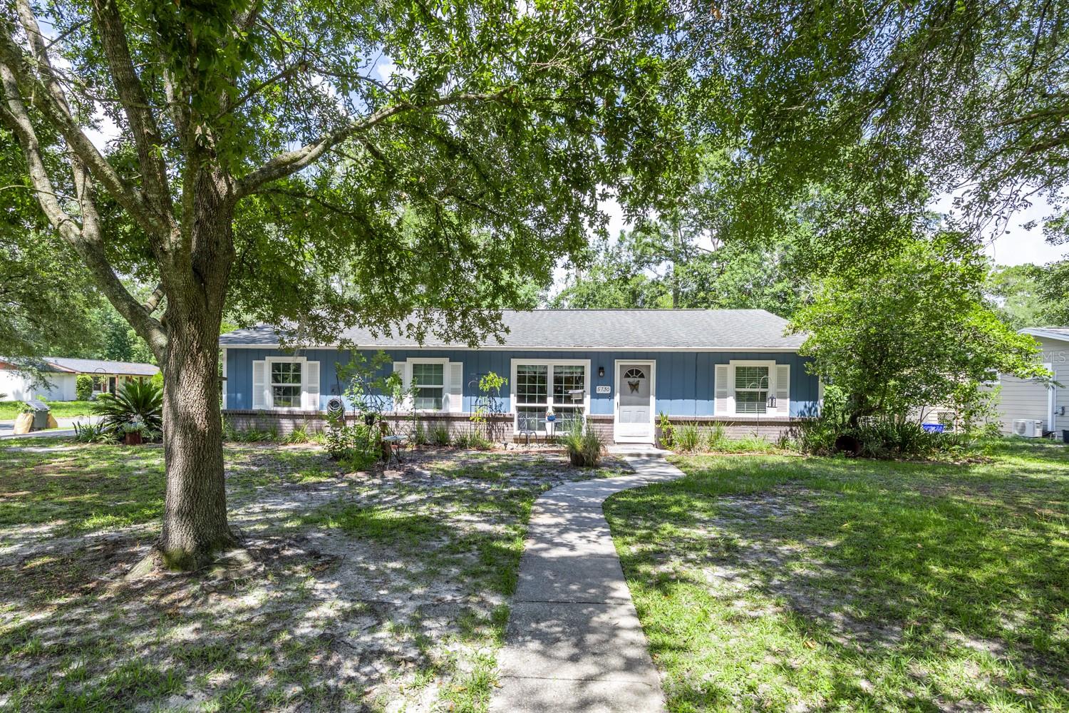 Welcome to 5730 NW 28th Terrace—a lovingly maintained modified ranch in Gainesville’s Northwood Pines. This 3-bedroom, 2-bath home offers 1,267 square feet of smart, inviting living space that blends vintage warmth with everyday functionality. Step inside to a formal living and dining area that sets a polished first impression—perfect for keeping tidy or hosting guests. Beyond, through a pocket door, the heart of the home opens up: a spacious kitchen with generous prep space and breakfast bar, flows directly into a cozy den with a floor-to-ceiling brick faced wood-burning fireplace and rich pecky cypress walls. A large sliding glass door connects this central living space to the backyard, where you’ll find lush landscaping, a pergola-covered patio, and a fire pit area—all fully fenced and remarkably private. The home’s layout places all three bedrooms along one side, flowing from front to back rather than directly across from the main living area, with pocket doors offering quiet separation between public and private spaces. Whether you need a retreat for remote work, rest, or play, this home lives much larger than its square footage suggests. Upgrades include gas HVAC and water heater, newer windows, a sprinkler system, two-car garage with storage cabinets and room to work on your projects, and termite bond. Located on a corner lot in a community-oriented neighborhood just minutes from shopping, dining, top schools, medical centers, UF/Shands/VA, and the airport, this home offers comfort, connection, and lasting value.