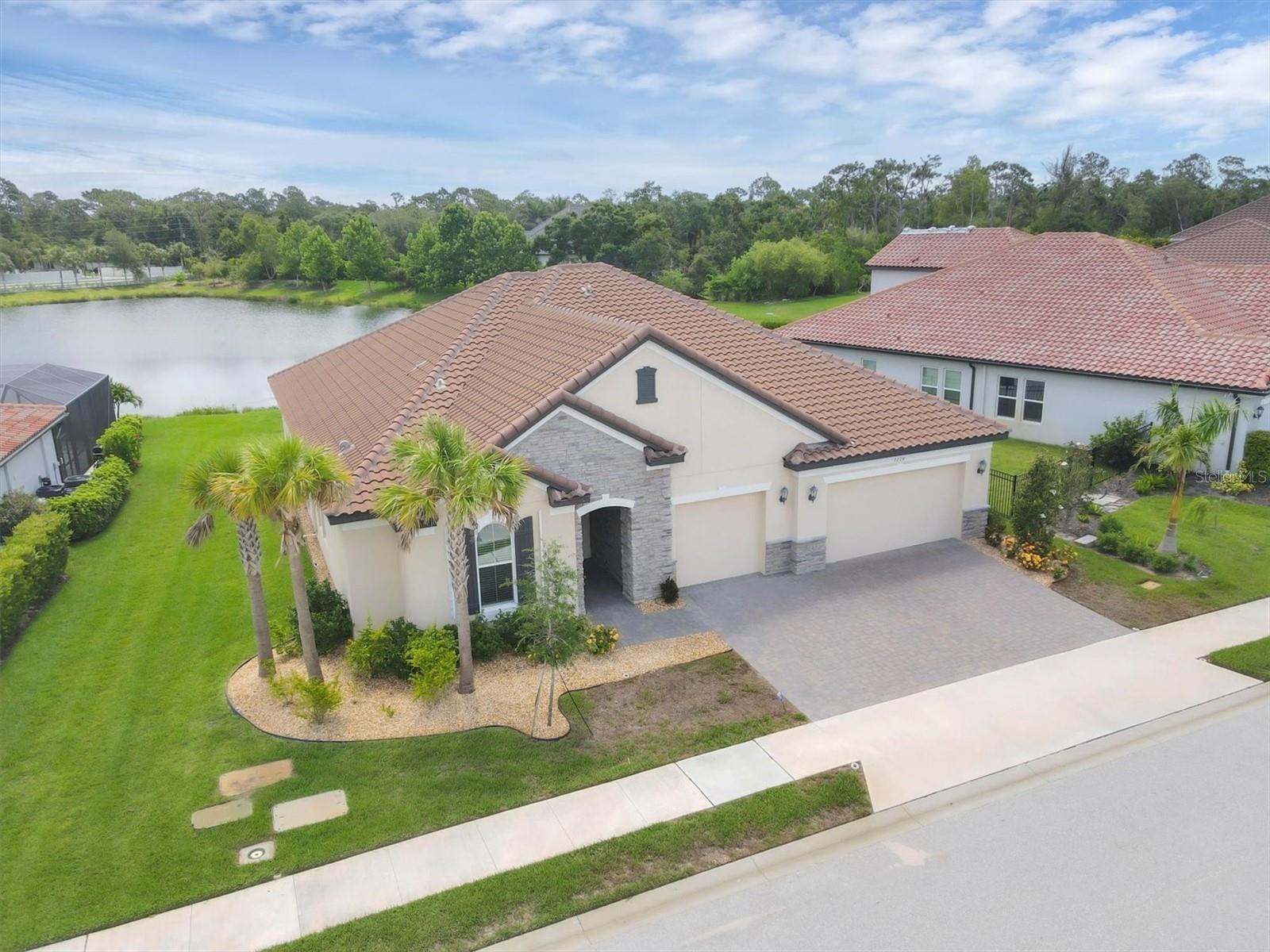 One or more photo(s) has been virtually staged. Welcome to 7228 Great Egret Blvd. – a beautifully designed Ashwood model by Meritage Homes, nestled in the gated community of Heron Landing in Sarasota. Built in 2022, this expansive single-story home offers 4 bedrooms, 3 bathrooms, and over 3,300 square feet of thoughtfully crafted living space. As you enter you are greeted with high ceilings and an open, light filled floor plan. There is a perfectly positioned office with double doors that can also be used as a playroom, fitness area or with the addition of a closet an extra bedroom. The spacious great room has a wall of sliding glass doors that frame your serene lake views, and is open to the stunning kitchen and breakfast nook. The kitchen is complete with a large island, upgraded cabinetry, stainless steel appliances, a walk-in pantry, built in coffee bar and opens to the separate formal dining room for ease of entertaining or every day living. The three guest rooms are all perfectly appointed; one is in the front of the home with a full bathroom and the other two are located on the opposite side of the home and share a large bathroom. Retreat to the primary suite boasting views of the lake, a large tray ceiling and en-suite with dual sinks and oversized zero entry shower – the perfect place to unwind at the end of the day. Every detail has been considered with a large inside laundry room, 8’ interior doors, hurricane shutters, mudroom/owner’s entry for additional storage, a three-car garage complete with an electric vehicle charger pre-wire and smart home technology with security system, video door bell, irrigation and entry lock all controlled by your phone! Step outside to the extended private covered patio and enjoy peaceful views. If you envision a pool in your backyard, this home has been prewired for a pool and spa; create your own personal oasis with the perfect backdrop. This location is ideally located less than 2 miles from I-75, a short drive to the world-renowned beach of Siesta Key and the vibrant arts, culture and dining of downtown Sarasota. With low HOA fees, no CDD fees and located in an A rated school district this home truly blends comfort and convenience. One or more photo(s) has been virtually staged.