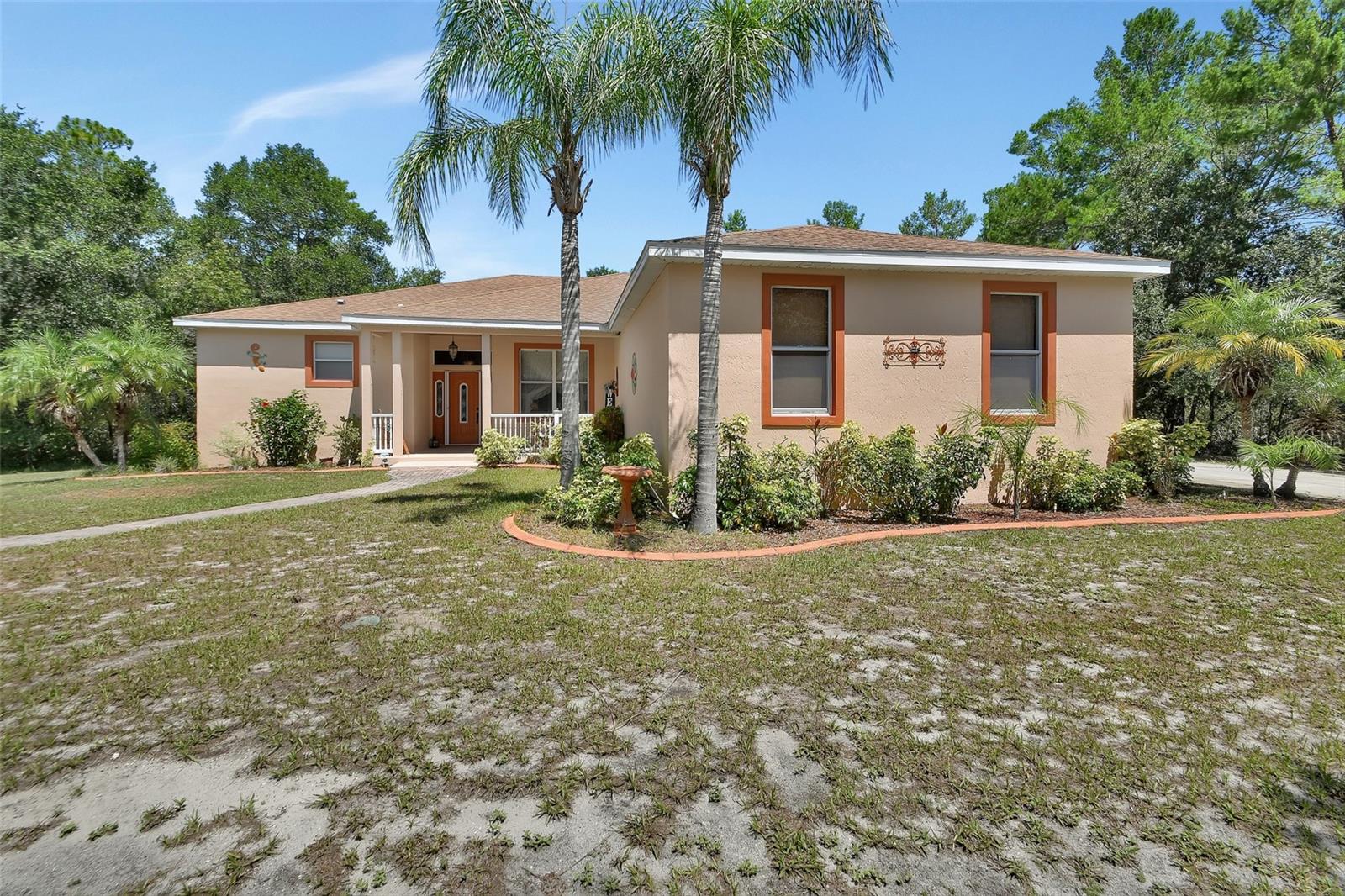Spacious 3-bedroom, 3-bath concrete BLOCK home with bonus room on 2.87 acres in the desirable Domingo Reyes area, offering private access to Lake Mamie for canoeing, paddle boarding, or kayaking.
Welcoming front porch says come and relax. Inside you’ll find 10 ft ceilings, architectural nooks and shelves, formal dining room, a large living/family room open to the kitchen with spacious breakfast nook, and French doors leading to a 37’x10’ screened lanai with multiple seating areas and ceiling fans. All interior common areas are tile and bedrooms have comfy carpet. Kitchen has newer stainless appliances, Quartz counters, breakfast bar, recessed and pendant lighting. Plenty of space at the dinette! The split-bedroom plan includes a Jack & Jill bath between bedrooms 2 and 3, each with its own closet and sink area, with pocket doors separating the bath and commode area. The relaxing primary suite features two walk-in closets, an en suite bath with a spacious tiled walk-in shower (6’x4.5’ with seat), privacy block window for great light, dual sinks, linen closet, and water closet. There is a 3rd full bath with exterior to Lanai. Need a 4th bedroom? The 9x8 office could work!
Outdoors, enjoy a covered gazebo with electric paddle fan, grill area, and separate fire pit. Attached 2-car garage has exterior concrete parking and crushed stone for additional parking. YES there is space for RV, trailers, or boats. CIRCULAR DRIVE for the big vehicles. A 40’x30’ METAL BUILDING (2019) with insulated ceiling and walls, new mini-split for AC and HEAT, two 10’ roll-up doors, and a pedestrian door, adds excellent storage or workshop space. Carport to right of workshop Does Convey.
Utility room with washer/dryer and abundant cabinetry. Well and Septic for lower utility bills. Irrigation! PRIVATE feeling but conveniently located near shopping, dining, and grocery stores, with easy access to I-4 for quick trips to Daytona Beach, Orlando, the airport, and area attractions.