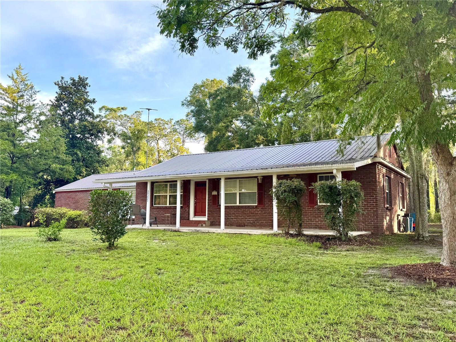 MOTIVATED SELLER due to relocating!! Double lot close to downtown!! Don’t miss the opportunity to own this charming brick home on almost 3/4 of an acre in the heart of HIGH SPRINGS! Located on a desirable corner lot with one of the highest elevations in the city, this lot can be split with the potential for TWO residential properties. Just a short walk to parks, restaurants, and local schools, you can experience a quaint, small town feel with all the modern conveniences. The spacious yard and seamless floorplan make this home ideal for raising a family or entertaining. The split level design and dual living areas provide the potential for an income producing suite. This 3-bedroom, 3-bathroom home features a formal living room, dining area, and a spacious family room. Uncover original hard wood floors that are protected under laminate. The converted garage, complete with full bath and indoor laundry, offers flexible use as a third bedroom, in-law suite, or space for your favorite hobbies. Enjoy outdoor living with the full-length rear porch, carport, and a generous backyard—perfect for gatherings, RV or boat parking, and more. The large auxilliary metal storage building provides air conditoned space for hobbies and storage. Close to Gainesville, Lake City, Shands and the VA, ony minutes from shopping and Florida's natural springs such as Ginnie and Gilchrist Blue. There is endless potential in this prime location!! Seller to contribute up to $3500 in closing costs! Call today!