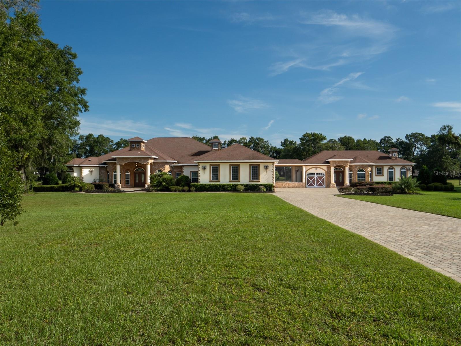 Located in NW Ocala within Saddlebrook Equestrian Park, this 5+ acre property is just 7 minutes from the World Equestrian Center and 15 minutes from HITS! Offering both comfort and versatility, the property includes a main residence and a connecting guest house. The main home features 4 bedrooms, 4 full bathrooms, and 1 half bathroom with tile flooring throughout. Tray ceilings with wood accents add warmth and character, while the master suite includes a spacious bathroom with a walk-in shower and soaking tub. The chef’s kitchen is well-appointed with stainless steel appliances, a large island, and abundant counter and storage space. Designed for both everyday living and entertaining, the home also includes a 5-car garage, a screened-in pool with water features, an outdoor bar, and a fireplace/lounge area. Connected by a screened courtyard, the guest house provides its own entrance, a screened back porch, 1 bedroom, 1 full bathroom, and a kitchen. With matching tile flooring, tray ceilings, and independent living areas, the guest house complements the main home while offering privacy for visitors. This property combines convenience, functionality, and equestrian potential in a sought-after location—an excellent choice for those looking to enjoy Ocala’s premier horse country lifestyle.