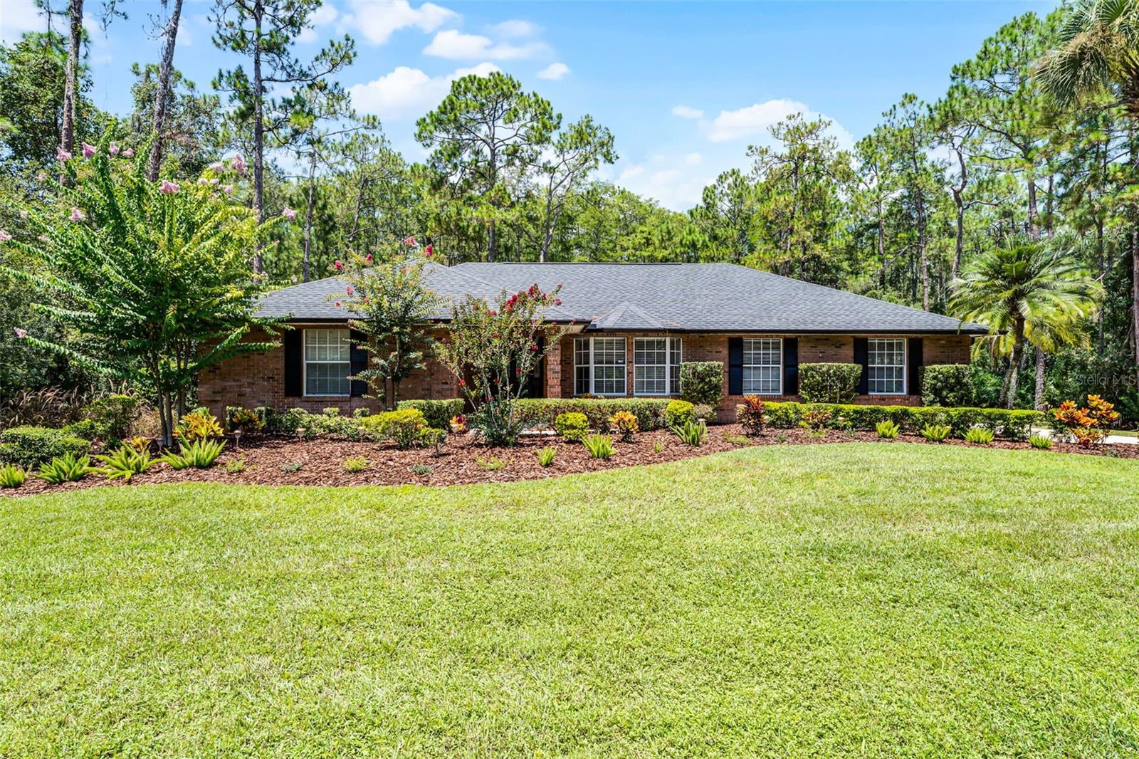 One or more photo(s) has been virtually staged. This property qualifies for a credit up to $10,875 through the seller's preferred lender / Seller may consider buyer concessions if made in an offer ~ Perfectly nestled among the trees in the highly desirable Live Oak Estates community of Moss Park/Lake Nona, this one-of-a-kind single story POOL HOME on a full 1 ACRE ~ CONSERVATION LOT offers the ultimate in privacy, space and serene wooded views! With a NEWER ROOF (2021), a FRESHLY PAINTED EXTERIOR, and thoughtful upgrades throughout, this well maintained home is ready for its next chapter. Stepping inside you will immediately feel a natural flow through the spacious floor plan, where WOOD & TILE FLOORS, high ceilings, crown molding and skylights create a bright and welcoming atmosphere. The formal living room features French doors that open to the pool, while the formal dining area impresses with a bay window, chair rail detail, and more of the elegant crown molding. The heart of the home is the beautifully updated kitchen offering desirable white cabinetry, a tiled backsplash, pendant lighting, STAINLESS STEEL APPLIANCES, breakfast bar, and seamless connection to the casual dining area and family room – ideal for everyday living and entertaining. Your PRIMARY SUITE is a spacious tranquil retreat with plantation shutters, DUAL WALK-IN CLOSETS, and a well appointed en-suite bath boasting dual sinks, a jetted tub, separate shower and private access to the pool. Bedrooms two and three share a second full bath also with double sinks, perfect for guests or family. The fourth bedroom is a true standout: an ACCESSIBLE IN-LAW SUITE with its own private bath (including a walk-in tub), expansive WALK-IN CLOSET, more of the elegant crown molding, and tranquil wooded views – ideal for aging family members, extended guests, or a young adult seeking more independence. Outside, the resurfaced SCREENED POOL and COVERED PATIO deliver a peaceful retreat, surrounded by lush landscaping/green space and the quiet beauty of the conservation beyond. There is a side-facing garage with an extended driveway, giving you ample parking and an attractive front elevation enhanced by the brick exterior and manicured landscaping. This home offers the space and flexibility for all stages of life – whether you are hosting holidays, working from home, or enjoying quiet lazy mornings watching the wildlife. With no rear neighbors, a LOW HOA, and easy access to SR 417, 528, Lake Nona, area lakes, and the Orlando International Airport you will enjoy the best of both worlds – convenience and tranquility. Opportunities like this are rare, a true 4-bedroom, 3-full bath pool home on a full acre conservation lot in a premier East Orlando location. Schedule your private tour today and discover why Live Oak Estates continues to be one of the area’s most treasured communities!