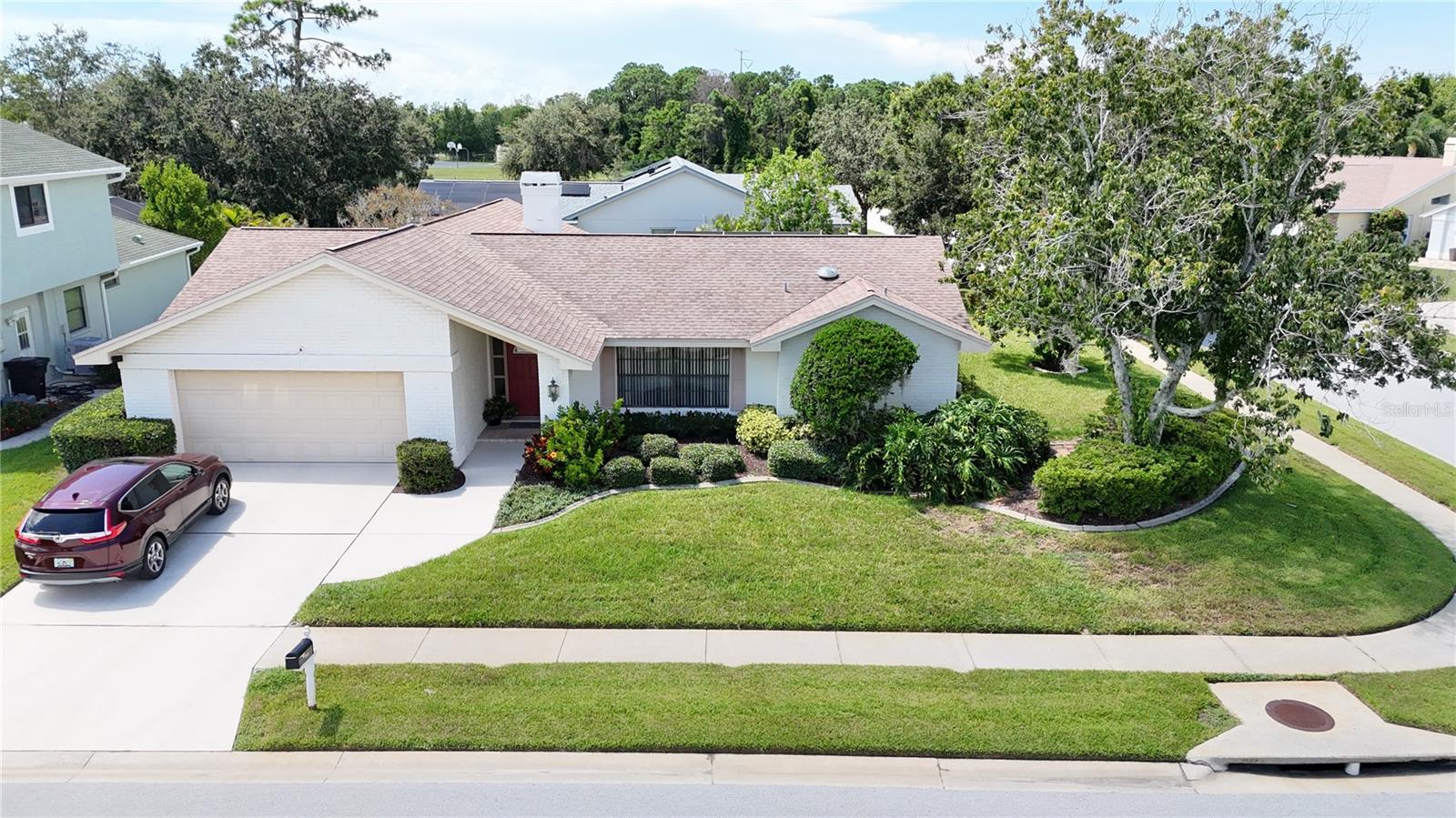 Welcome to this beautifully maintained 4-bedroom, 2-bath pool home in the desirable Amblewood Gulf Trace community of Holiday, Florida. Situated on a 0.23-acre landscaped corner lot, this 2,044 sq ft single-story residence offers cathedral ceilings, skylights, and abundant natural light. The spacious kitchen features solid-surface countertops, ample cabinetry, stainless steel appliances, and a convenient pass-thru window to the lanai for easy entertaining. The primary suite has a built-in closet and direct pool access, while the family room centers around a cozy wood-burning fireplace. Tile throughout the home ensures easy care.
Step outside to a screened saltwater pool and spa with Pebble-Tec surface, brick paver decking, jacuzzi, new fiber pool lights with remote, and a covered patio. The expansive lanai can be fully enclosed with seven sliding doors and includes a table and chairs that may convey. Recent updates include a 2019 AC, 2024 electrical pool panel, 2006 roof, upgraded 200 Amp electrical panel (2024), and a wireless Chamberlain MyQ garage door opener. Additional features include a Hunter wireless-controlled sprinkler system, dual-pane insulated windows and sliders, Kevlar hurricane screen protection system, finished garage, and multiple parking options. Conveniently located near shopping, dining, public transit, and Gulf beaches—this move-in-ready home is perfect for enjoying the Florida lifestyle.