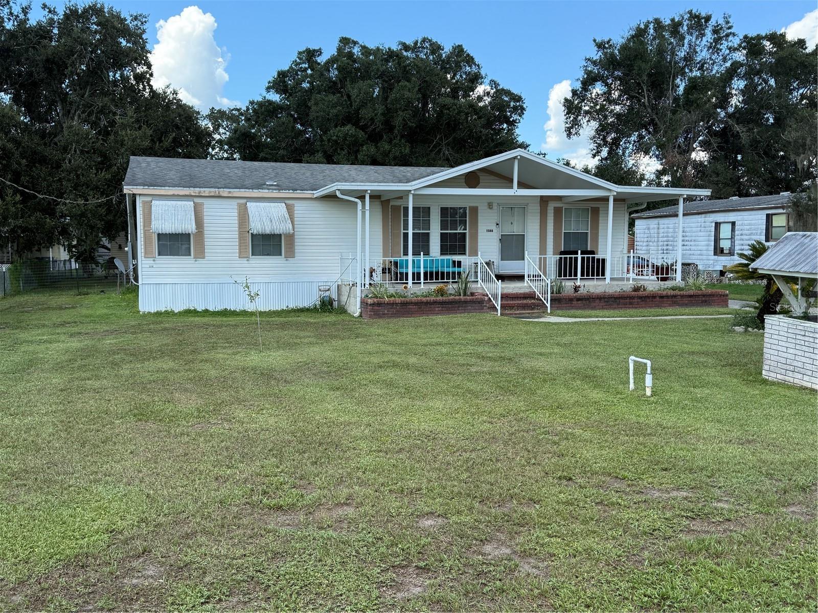 Welcome to this beautifully maintained 3-bedroom, 2-bathroom manufactured home, built in 2005 and offering comfort, updates, and plenty of space both inside and out. Step inside to find a split floor plan with fresh interior paint and new luxury vinyl flooring throughout. The spacious primary suite features a large walk-in closet and a private bathroom with a soaking tub and separate shower. An inside laundry room adds everyday convenience. Enjoy Florida living on the oversized front porch, the screened and vinyl-enclosed lanai, or in the fully fenced yard with chain-link fencing—perfect for pets or outdoor activities. Two exterior sheds provide excellent storage, while a carport offers covered parking. Practical updates include a brand-new 2024 central AC unit. The property sits in Flood Zone X, meaning no flood insurance is required, and best of all—no HOA! Located in the county, this home offers the best of quiet living with easy access to town.