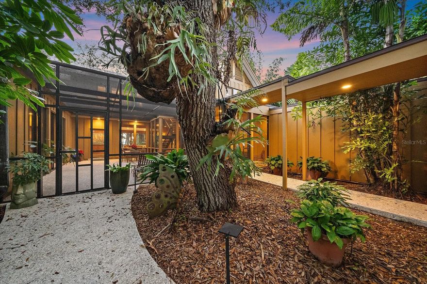 Architecturally distinctive and exceptionally private, this furnished Mid-Century Modern residence is available for annual lease in one of Sarasota’s most sought-after West of the Trail locations. Ideally positioned near Siesta Key Beach, Siesta Village, and the shopping and dining of Southside Village, this home offers a rare combination of space, privacy, and proximity to everyday conveniences. Designed to embrace natural light and indoor-outdoor living, the home spans approximately 3,668 square feet and features four bedrooms, including a loft-style bedroom, along with multiple flexible living spaces. Soaring ceilings, expansive walls of glass, and dramatic cypress detailing throughout create a warm yet modern aesthetic that feels both timeless and livable. The main living areas flow effortlessly, anchored by a striking wood-burning fireplace and an open kitchen designed for gathering and entertaining. Multiple patios and outdoor sitting areas extend the living space into the beautifully landscaped grounds, offering a sense of tranquility and separation while remaining close to Sarasota’s most desirable destinations. The upstairs primary retreat provides a private sanctuary with a spacious bedroom, spa-inspired bath, and a dedicated laundry area. 2 additional upstairs bedrooms offer comfortable accommodations for guests or household members with a Jack & Jill bathroom. On the main level, a guest suite and a versatile bonus room provide ideal space for a home office, media room, or fitness area. Set on a large, private yard with bay views, the property features a heated indoor lap pool, allowing for year-round enjoyment regardless of season. A two-car garage with electric vehicle charging station adds modern convenience, and pets may be considered on a case-by-case basis with owner approval. Located West of the Trail and just minutes from Siesta Key Beach, Siesta Village, downtown Sarasota, Sarasota Memorial Hospital, marinas, and top local amenities, this home delivers the perfect balance of privacy, space, and accessibility. An exceptional opportunity for those seeking a long-term luxury rental in a premier Sarasota location.