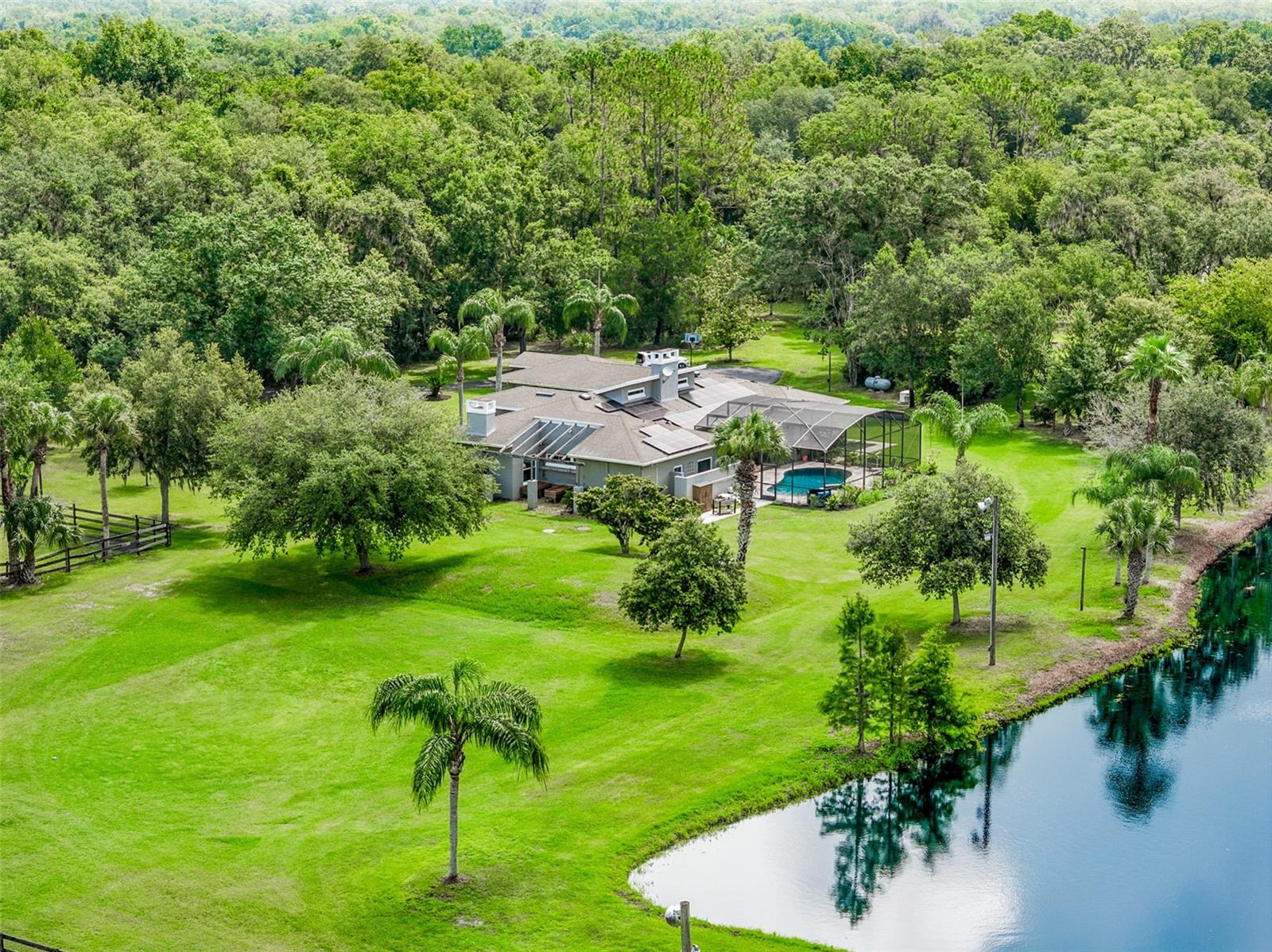 Your Own paradise!
Oviedo ranks among the top 50 cities to live in America, and this is country living at its finest—complete with A-rated schools in Oviedo and Seminole County!
This gated homestead offers seclusion without isolation, located just three miles from 417 and shopping. A long, winding driveway lined with canopied oaks leads to this one-of-a-kind 12.5-acre estate, which features a 2,777 square foot split-plan pool home, four grazing pastures, an open riding field (perfect for soccer, lacrosse, or football), and a 4–6 stall barn nestled in the southwest corner.
Step through the front doors into a spacious great room with vaulted ceilings, a modern fireplace, and a built-in entertainment nook. Two sets of French doors open to a large, screened-in lanai that opens to your outdoor oasis.
From the lanai, enjoy a swim in the solar-heated pool, relax in the hot tub, grill on the built-in gas BBQ, or simply take in the peaceful view of the 1.5-acre pond with a covered dock wired for power—ideal for entertaining or watching sports.
The spacious master suite includes a cozy sitting room with built-in bookcases and a gas fireplace, French doors to the lanai, and a large en suite bath with a soaking tub, shower, and dressing area. Two of the three additional bedrooms share a bathroom, while the fourth is a private en suite with pool access.
The newly remodeled kitchen is a chef's dream with stone countertops, a tile backsplash, a huge center island with cooktop perfect for entertaining, a large walk-in pantry, and a breakfast area overlooking the lanai and pond.
The barn and pasture occupy approximately 5 acres and are subdividable. The barn includes a large porch facing the pond, two dry storage bays for hay and bedding, and a 12x24 climate-controlled tack room with a toilet, washer, utility sink, and refrigerator. Two stalls have been converted for storage, leaving four stalls available for horses—each facing a pasture and capable of being paddocked for direct access. All stalls and pastures are equipped with automatic waterers. A 4-bay vehicle storage shed is located behind the barn.
Working from home? The 1,870 sq ft concrete block shop to the east of the home includes a 12x10 office, an air-conditioned woodshop, full bathroom, utility sink,and upstairs storage—ideal for remote work or hobbies.
Solar panels help reduce energy costs and boost sustainability, making this estate as smart as it is serene.
You will have endless possibilities on this Estate. Enjoy breathtaking sunrises on your walk to feed the animals and gorgeous sunsets from the dock as you unwind. If you're looking to connect with nature in a tranquil, private sanctuary, this ready-to-move-in home is your dream come true.