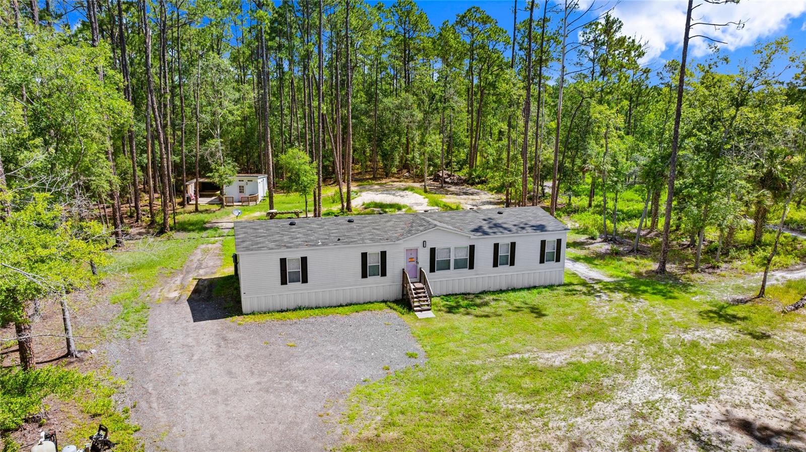Brand New Country Retreat with Bonus Tiny Home, Spa Deck & Outdoor Fireplace – Just 30 Minutes from the Beach! Escape the ordinary with this incredibly unique and newly built (2023) manufactured home, offering peaceful, spacious country living just a short drive from the Atlantic coast. Set on over an acre of open land, this property is ideal for homeowners, investors, or aspiring homesteaders. The main home features 4 generously sized bedrooms, including 3 with walk-in closets, 2 full bathrooms, a bright living room, a separate family room and a convenient laundry room. Whether you're seeking space for your family, hobbies, or storage, this layout offers room to breathe in every direction. A detached “Tiny Home” offers even more flexibility with its private entrance and built-in cabinetry, making it the perfect space for guests, a home office, in-law suite, or creative retreat. Step outside and enjoy the true magic of this property: a spacious attached deck with a glamorous spa, perfect for relaxing under the stars, and a custom outdoor fireplace with a built-in seating area—an ideal spot to gather with friends, enjoy quiet evenings, or host unforgettable country nights. Already listed on popular rental platforms, this home has a proven track record as a successful short-term rental, making it a smart investment opportunity as well as a peaceful primary residence. Even better, the adjacent vacant lot is also available for purchase—call the listing agent for more details. Brand new. Beautifully private. Thoughtfully designed. This is more than a home—it’s your next chapter.