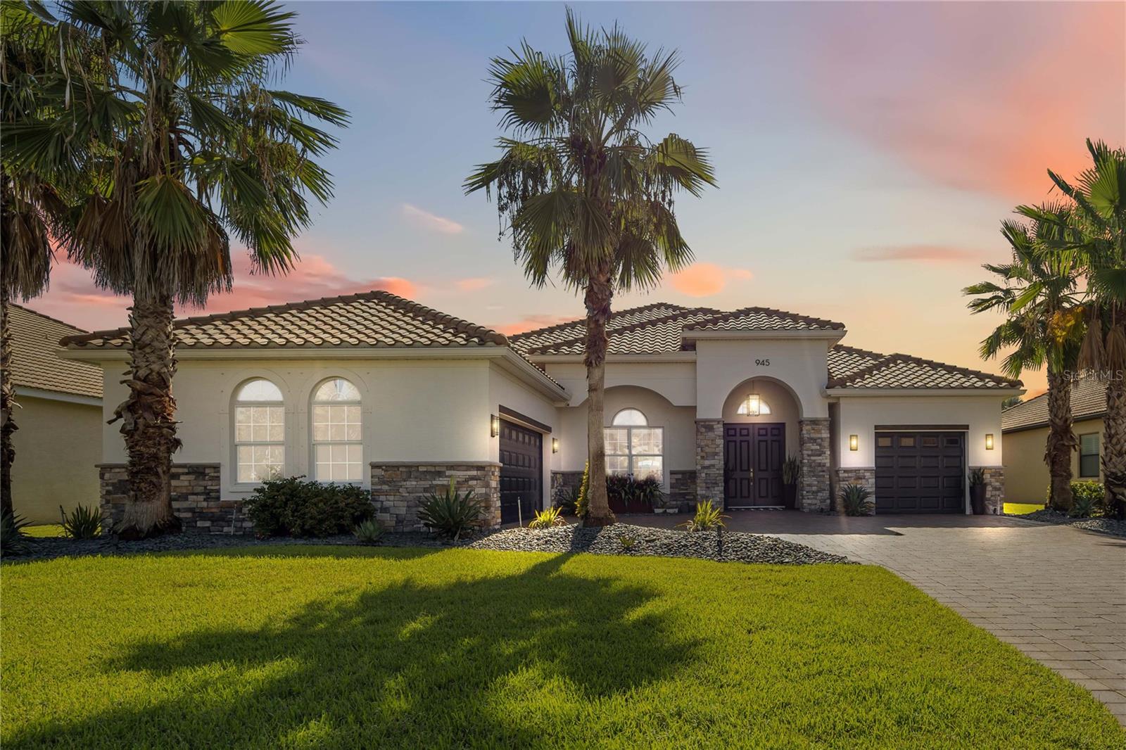Welcome to 945 145th St Cir NE, Bradenton, FL – a meticulously upgraded 3 bedroom + large Bonus Room, 3 bath 2787 sq. ft. pool residence, designed for both everyday comfort and elegant entertaining. An expansive private rear yard too! From the moment you arrive, the home makes an impression with its real stone columns, fresh exterior paint, upgraded landscaping with custom lighting, and paver driveway and walkway. Step inside to find rectified Italian porcelain flooring flowing through the main living areas, complemented by engineered hardwood in the bedrooms. Arched entries, rounded corners, vaulted tray ceilings, and crown molding enhance the open layout, while collapsing pocket sliding glass doors seamlessly connect the Great Room to the outdoor living space. Throughout the home, 5 ¼” baseboards and 8-foot doors add a refined, custom finish. The heart of the home is the upgraded kitchen, featuring dovetail soft-close cabinetry with crown molding, granite countertops, a counter-height peninsula, under-cabinet lighting, and a vented glass/stainless-steel hood. A custom walk-in pantry, bar nook with quartz countertop and wine fridge, and upgraded fixtures complete the space. The laundry room is equally well-appointed with cabinetry, sink, washer/dryer, and an additional storage closet. The oversized media room, spanning over 400 sq. ft., offers flexibility to serve as a second master suite or entertainment space. The primary suite itself is a retreat, featuring custom dual walk-in closets with built-ins, blackout curtains, and a luxurious bath with a soaking tub beneath a chandelier. Outdoor living is truly exceptional. A screened, extended lanai of over 1,000 sq. ft. showcases upgraded pavers, ceiling fan, and it’s already plumbed for an outdoor kitchen and TV wiring. The heated saltwater pool with brick coping is paired with a lighted spa cascading into the pool. For peace of mind, the lanai is protected by UV-rated hurricane screens, with storm shutters for windows and doors. The lushly landscaped yard includes four mature coconut palms and over 50 magnolia trees, all maintained by an automatic sprinkler system. Additional highlights include epoxy-coated garage floors with “Florida basement” for raised shelf storage, monitored outdoor cameras and motion lighting for extra security, tinted double-pane windows, and upgraded chandeliers and fixtures throughout. This home combines high-end finishes, practical upgrades, and extensive indoor-outdoor living – a rare opportunity in the gated community of Enclave at Country Oaks in Bradenton. View property website at: https://tours.snaphouss.com/945145thstreetcirclenortheastbradentonfl34212?b=0