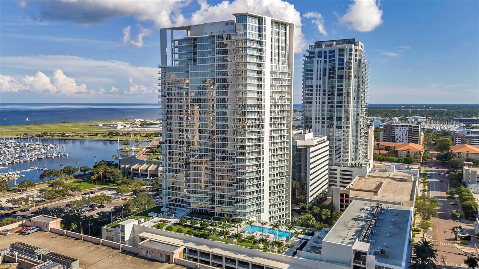One or more photo(s) has been virtually staged. LUXURY FULLY FURNISHED CONDO IN DOWNTOWN ST. PETE | ULTIMATE DOWNTOWN BEACH DRIVE LOCATION | 2 BEDROOM | 2 BATHROOM | 2 PARKING SPACES RESIDENCE | Embrace sophisticated urban living in this meticulously appointed high-rise corner sanctuary in the cultural heart of Downtown St. Petersburg. This distinguished residence offers an expansive 1,370 sq. ft. interior complemented by a sweeping 405 sq. ft. private terrace—creating a seamless indoor-outdoor living experience totaling 1,775 sq. ft. Floor-to-ceiling windows frame spectacular panoramic city views while bathing the residence in natural light throughout the day. Offering 2 bedrooms and 2 full bathrooms, the primary suite features a spa-inspired ensuite with dual vanities and a generous walk-in closet, while a second bedroom with full bath provides perfect accommodations for guests. There is also a desk area with an office chair for ease to work from home. The gourmet kitchen showcases premium European cabinetry, sleek top-tier appliances, and rich Wenge hardwood floors that flow throughout the thoughtfully designed living spaces. In-unit laundry adds convenience to luxury. Step outside your door to discover an exclusive lifestyle amenity floor featuring a state-of-the-art fitness center, stunning rooftop infinity pool, and sophisticated clubhouse—all offering unparalleled views of Tampa Bay, the St. Pete Pier, Al Lang Stadium, and the Grand Prix circuit. Experience true lock-and-leave convenience with two reserved covered parking spaces and comprehensive services, including cable, internet, water, sewer, and trash all included. Your downtown adventure awaits with world-class dining, galleries, museums, waterfront parks, and boutique shopping just steps from your door. HOA approval required ($100 application fee). Annual lease preferred and a minimum of 6 months lease considered. Unfortunately, we cannot accept pets in this unit. The tenant only pays electricity.