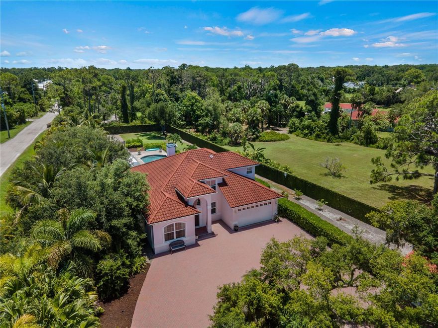 ***SELLER FINANCING AVAILABLE*** 
DECRA METAL TILE ROOF • OWNED SOLAR PANELS • IMPACT WINDOWS AND DOORS • HEATED SALTWATER POOL & SPA • LEVEL II EV CHARGING

Come discover this unique and secluded Florida Estate providing solid peace of mind during storm season. This exceptionally private and energy efficient two-story home is situated in the midst of lush native landscaping on a massive 1.12 acre gated property around the corner from Manasota Beach. The home sustained no damage during recent storms thanks to major structural improvements throughout.
The property is fully enclosed with an 8-foot reinforced concrete wall and gated access at both the front and rear creating a secure, private setting with no HOA restrictions. As you enter through the gate into the expansive paver courtyard, the setting creates a true sense of separation from the outside. An 18’x45’ PebbleTec gas heated pool and spa is centered in the back yard just steps away from the screened lanai. Other outdoor features include a 75’ x 50’ deck, a 50’ pergola with partial operable roof, secure space for RV and boat parking, and an incredible entertaining area.
A fully remodeled main-level primary suite features dual vanities, a walk-in shower, and custom closet. The kitchen features granite countertops and gas appliances, including a Wolf range. Interior finishes include a mix of Acacia wood, tile, and carpet, along with plantation shutters throughout. Additional features include a two-story family room with a gas fireplace, formal dining area, and a dedicated office/den with a built-in bookcase.
The second floor includes three additional bedrooms and a full bath off of the loft area. A pocket door provides added privacy for two of the bedrooms and bathroom.  The attached two-car garage includes an Electric Vehicle Charging Station for convenience and efficiency. A roomy detached garage allows for additional storage and a workspace, plus room for vehicles or toys. The property also includes a new irrigation system, underground 275 gallon propane tank, and outdoor kitchen propane hook-up. Optional access to the Manasota Beach Club is included, and the public boat ramp and beach are just around the corner. Come experience this rare gem in the heart of Old Florida!