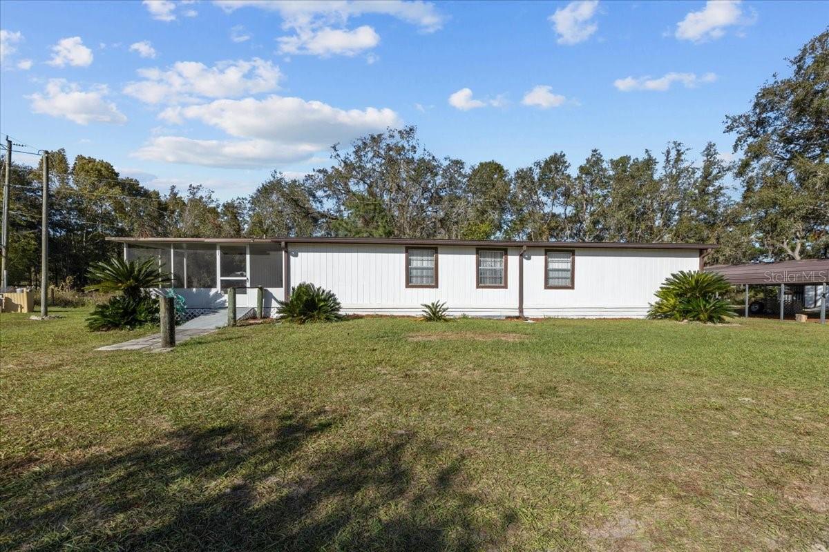 Beautiful property located in Bronson FL. surrounding by several lakes and wide open spaces. This home is a very well maintained 2/2 DWMH located on .52 acres. Bronson is conveniently located a short distance to Gainesville and Ocala Fl. When entering the home you'll see this nice front screen porch perfect for sitting and enjoy the quiet countryside. Front door open to a foyer and over sized living room (that had a 3rd bedroom) to make it extra large, could easily be converted back. Nice large dining room and open kitchen with lots of space. Master bedroom is spacious with bathroom with a combo tub/shower and vanity. Guest bedroom is spacious along with guest bathroom. You also have an additional room that can be used as a small Florida room, office etc. and a nice laundry room. Outside the yard is the perfect size for low maintenance, a 2 car detached carport and nice workshop/shed with lean too on both sides. This property is stunning, well maintained and perfectly located near town for all the amazing amenities . Accepting CASH,Conventional and VA Loans, call today for YOUR Tour! Some images are virtually staged.