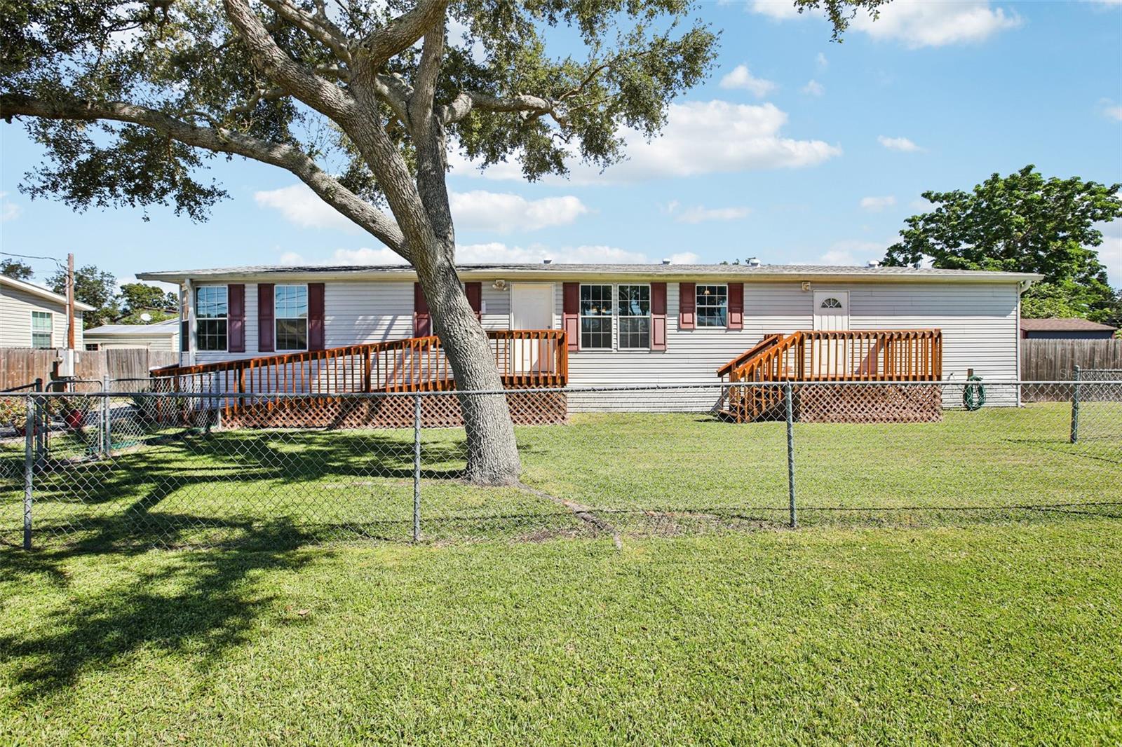 Perfectly positioned in the heart of Tampa Bay, this quality-built 2010 Jacobsen home offers the best of comfort and convenience. Fully HUD-certified and eligible for FHA, VA, and conventional financing, this 3-bedroom, 2-bath manufactured home spans over 2,100 square feet of interior living space and sits on a generous 0.21-acre lot. The spacious front yard offers ample curb appeal, with a portion already fenced — ideal for pets or outdoor play. Step inside to a bright, open floor plan where vinyl flooring extends through the kitchen and dining area before transitioning to carpet in the main living room—offering both style and comfort for everyday living or entertaining. The oversized kitchen is a standout with abundant cabinetry and countertop space, a center island, stainless steel appliances including a brand-new refrigerator, built-in spice rack, and pantry. Just off the kitchen, you’ll find a convenient indoor laundry room (washer and dryer included!) that also opens to a massive walk-in storage area. The owner’s suite is generously sized with a walk-in closet and private ensuite featuring a large glass-enclosed shower. Interior French doors lead to a second family room with vinyl flooring, providing flexible space for a media room, playroom, office, or more. The desirable split-bedroom layout ensures privacy for all. Step outside from the laundry area onto the deck leading you to the fenced front yard. Around back, this home comes complete with not one but TWO sheds for on-site storage. Enhanced peace of mind comes standard with 3M security film on the windows—offering both added protection and UV ray blockage—paired with included hurricane shutters for ultimate storm readiness. Best of all—NO flood zone, NO HOA, NO lot rent, and YOU own the land! This prime location makes everyday living effortless — from quick grocery runs and local dining just minutes away, to weekend outings filled with live music and line dancing at Cowboy’s Dance Hall. Feeling adventurous? Head 20 minutes south to vibrant Downtown St. Pete for festivals, nightlife, and waterfront views, or take the same drive west to relax on our award-winning Gulf Coast beaches. Commuters will love the easy access to US-19 and the Gandy Bridge, putting Tampa International Airport just 25 minutes from your doorstep. With parks, recreation, shopping, dining, and entertainment in every direction, this is Florida living right in the heart of it all.